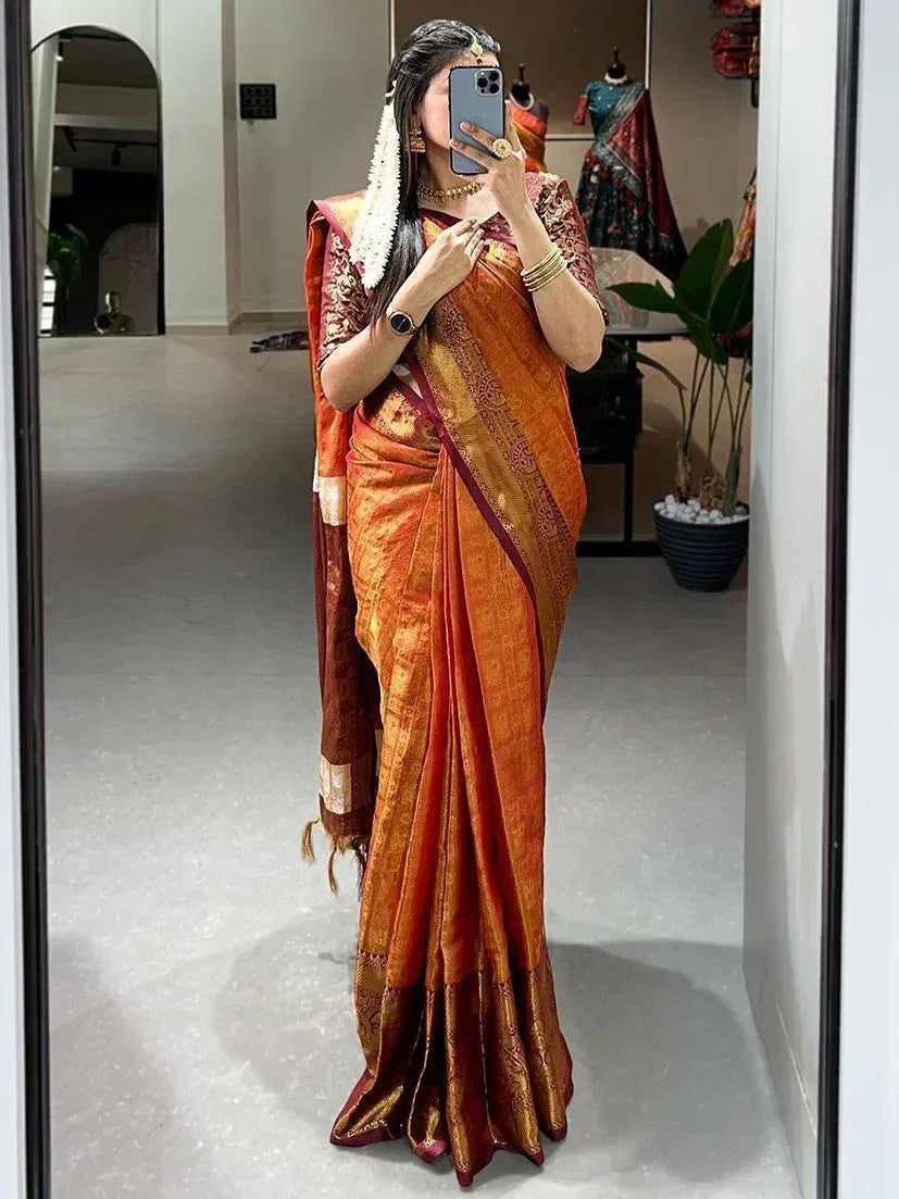 Woman in orange and maroon designer saree with gold embroidery, traditional Indian ethnic wear
