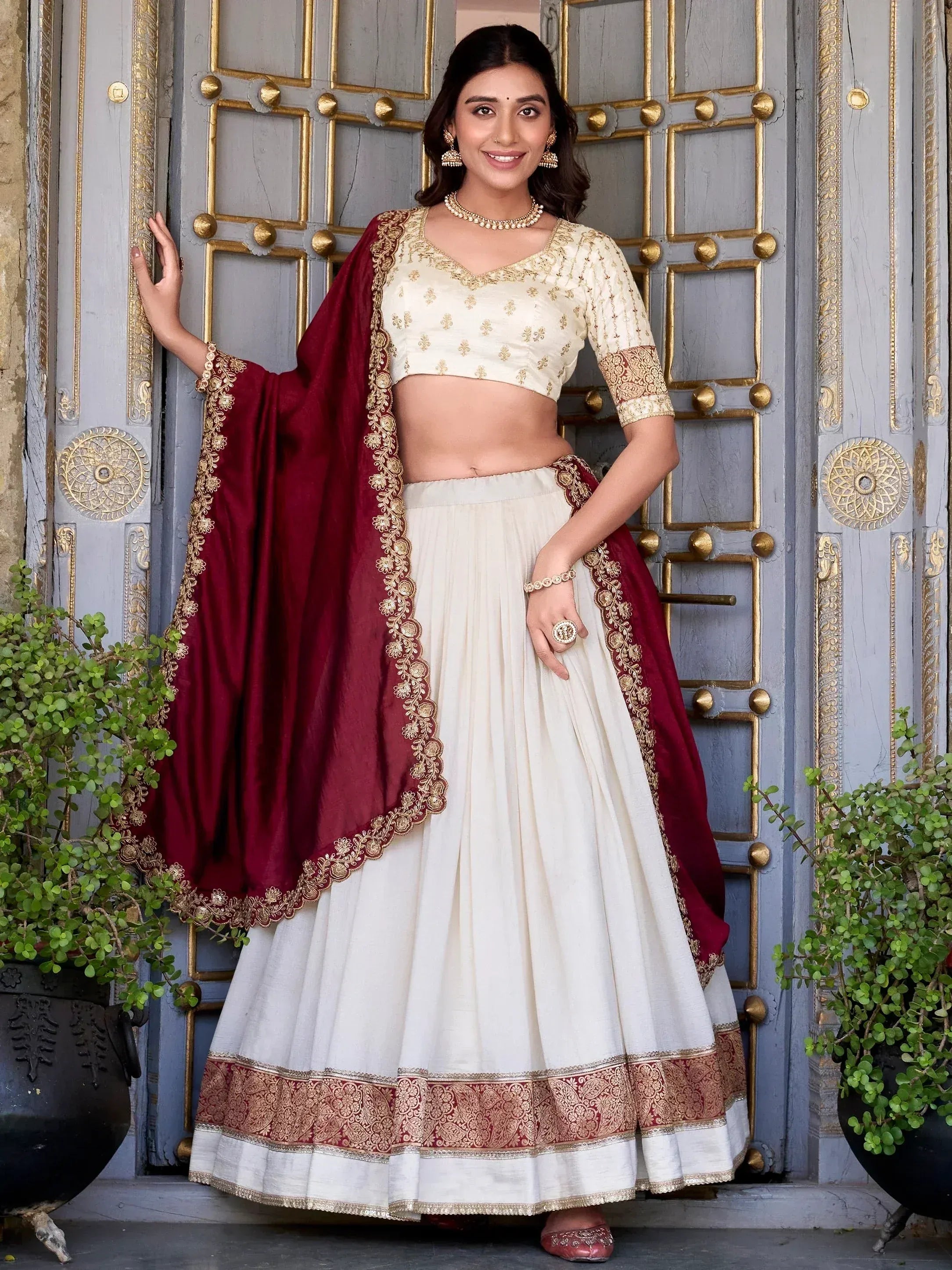 Cream and maroon embroidered lehenga choli with gold detailing, perfect for Indian ethnic occasions.