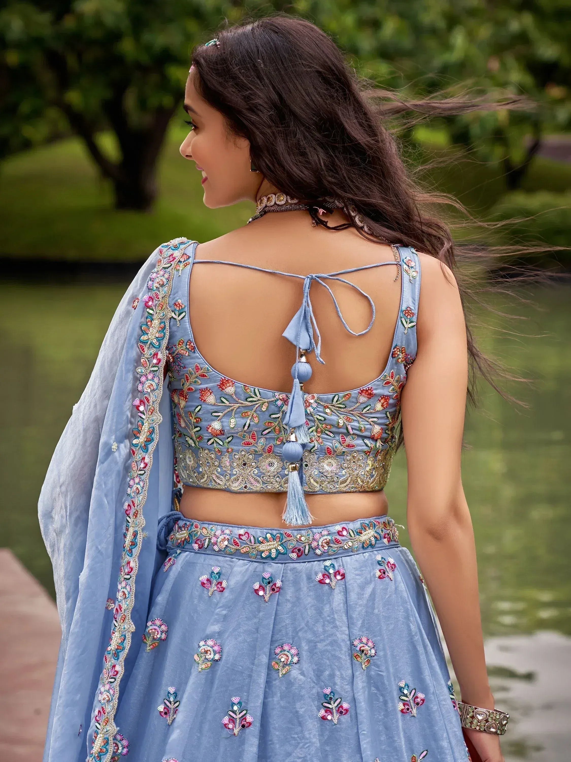 Blue embroidered lehenga choli with floral motifs, open back, and tassels, perfect for Indian ethnic wear.