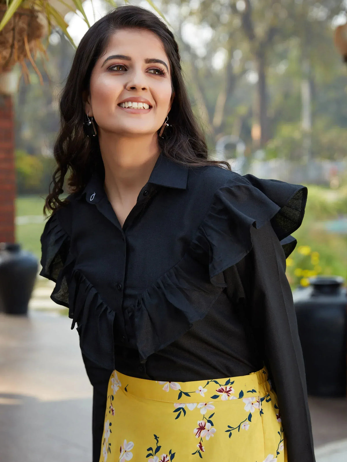 Woman in black ruffled blouse and yellow floral skirt, stylish ethnic wear for women