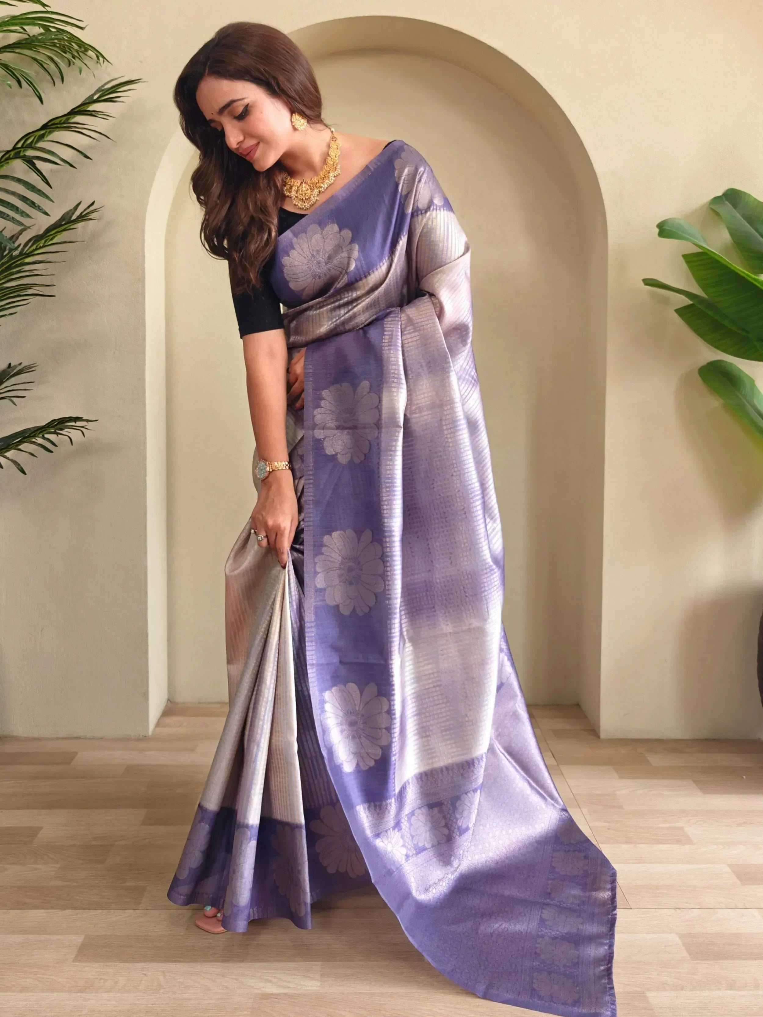 Woman in purple floral designer saree with gold jewelry, elegant ethnic wear for Indian occasions
