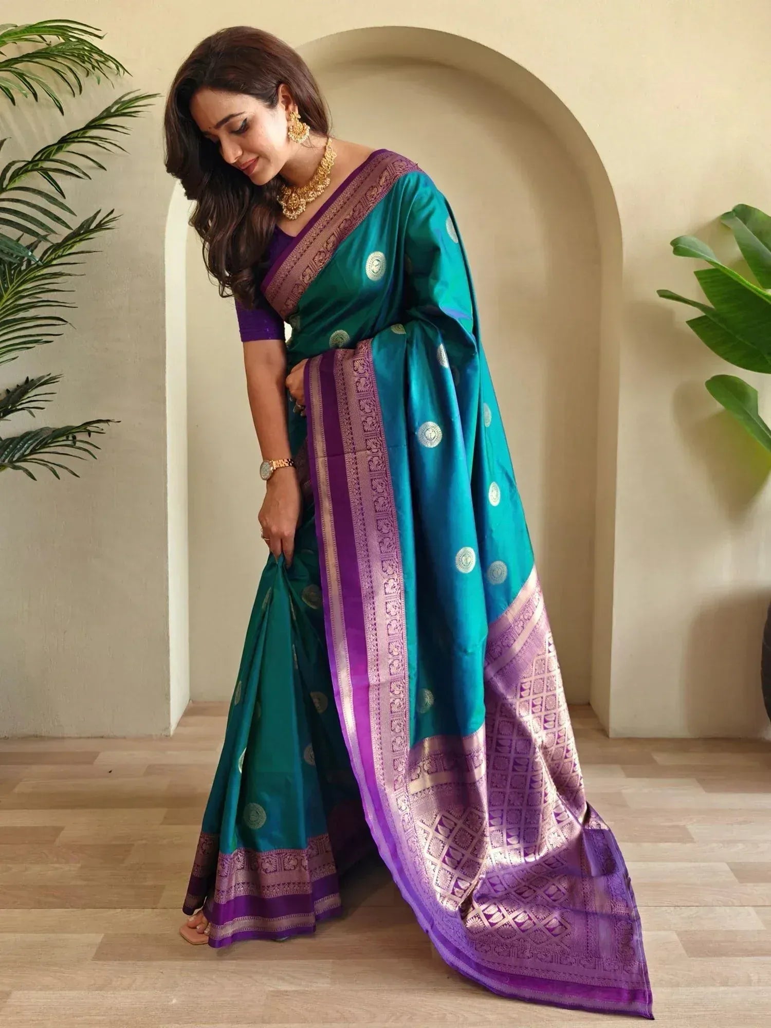Teal and purple designer saree with gold motifs and temple border, styled with matching blouse and jewelry