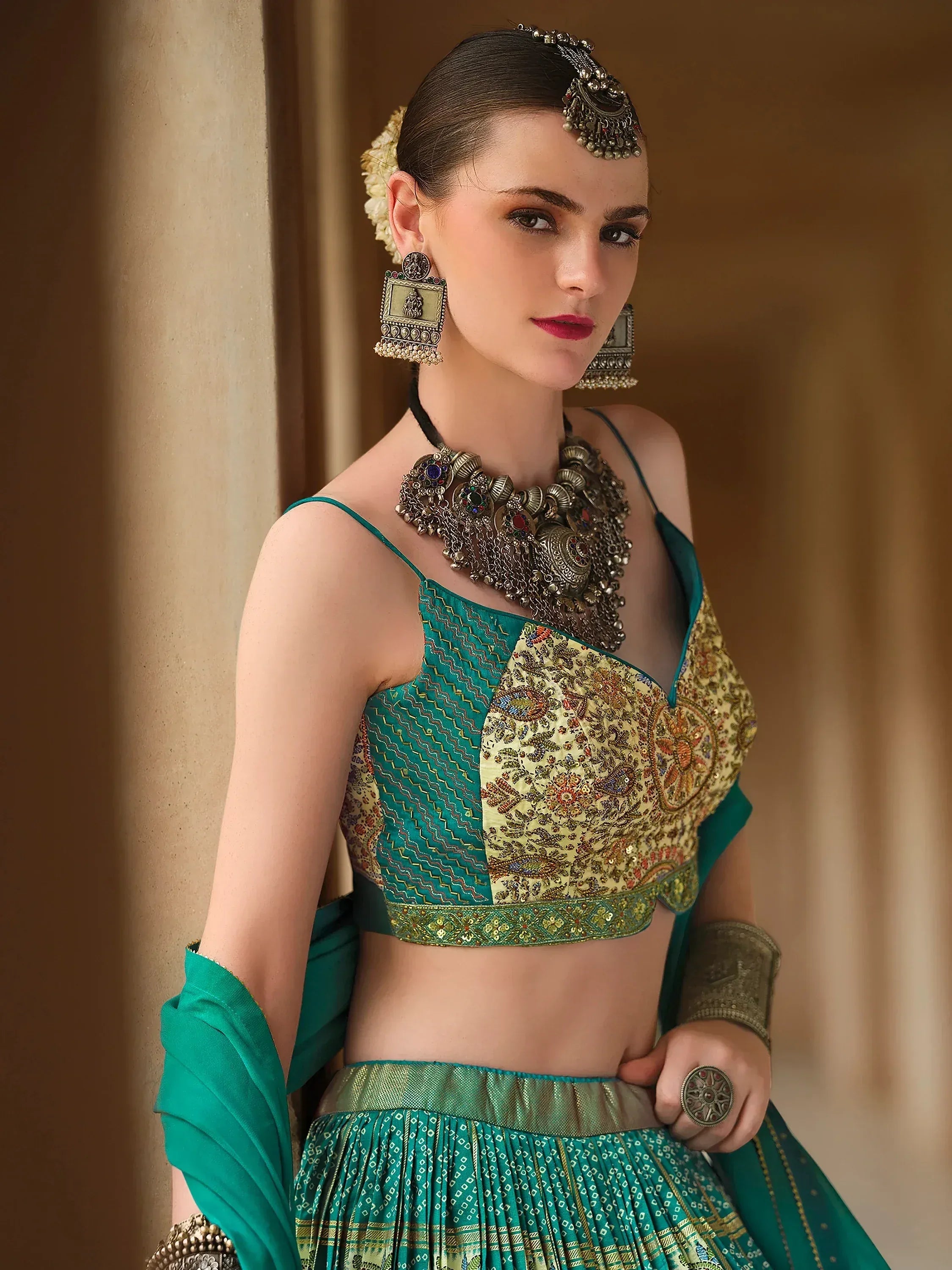 Woman in green and gold embroidered lehenga choli with traditional Indian jewelry