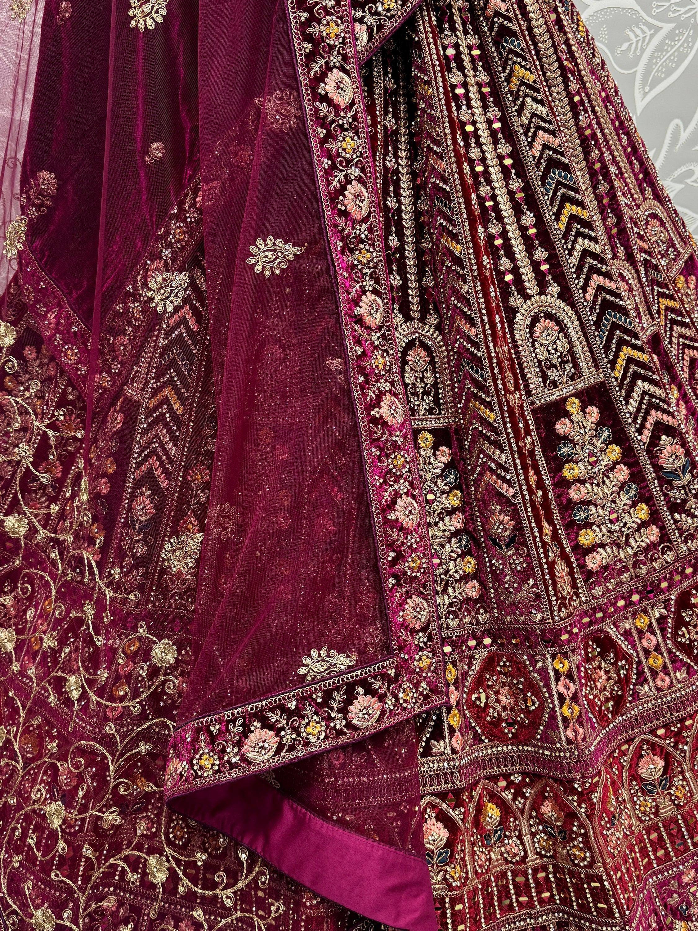 Luxury maroon velvet lehenga choli with intricate gold embroidery and floral motifs, perfect for Indian weddings.
