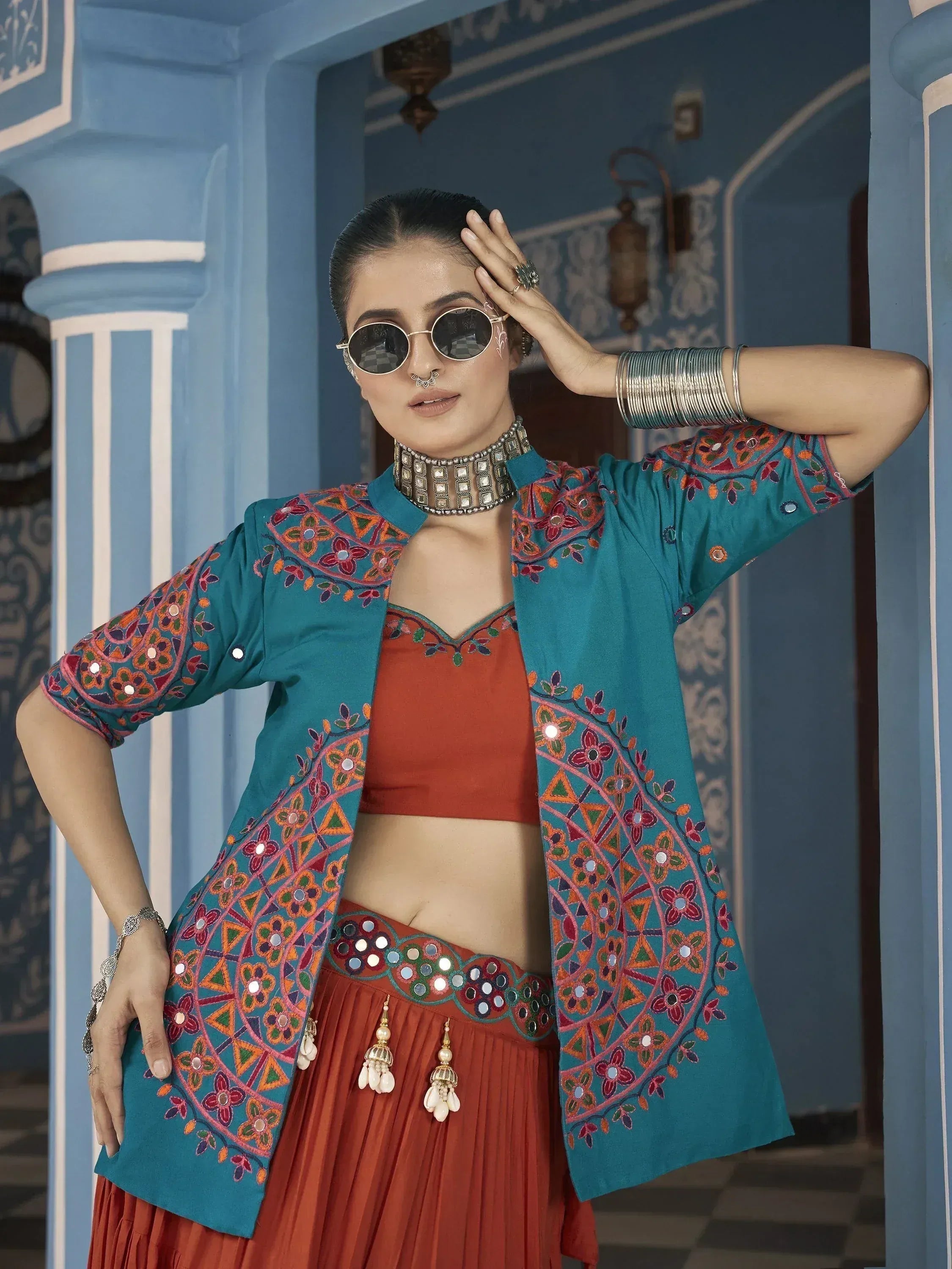 Ethnic wear with embroidered teal jacket and orange lehenga, styled with mirror work and jewelry