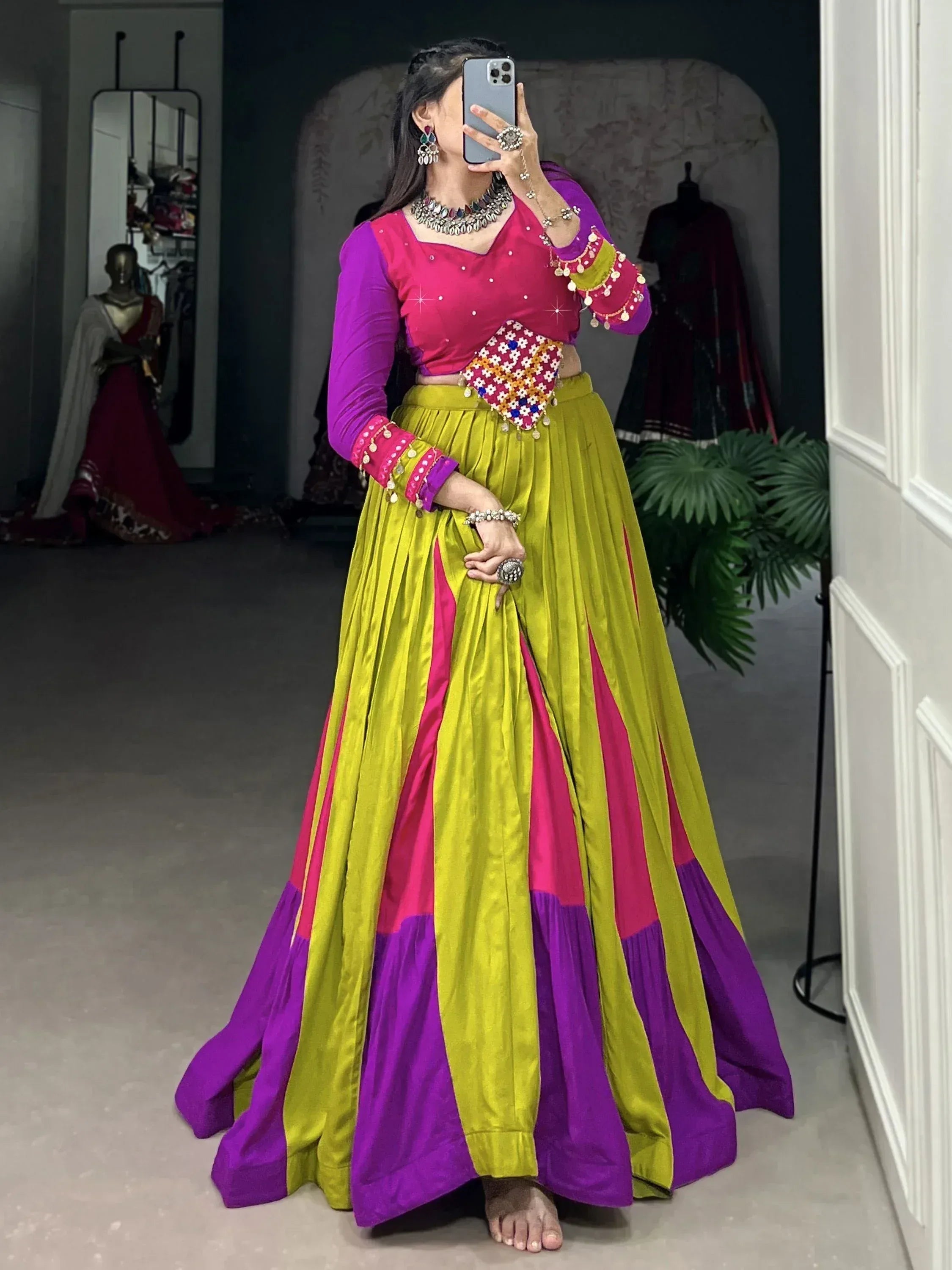 Vibrant Indian lehenga choli in pink, purple, and lime green with mirror work, perfect for festive occasions.