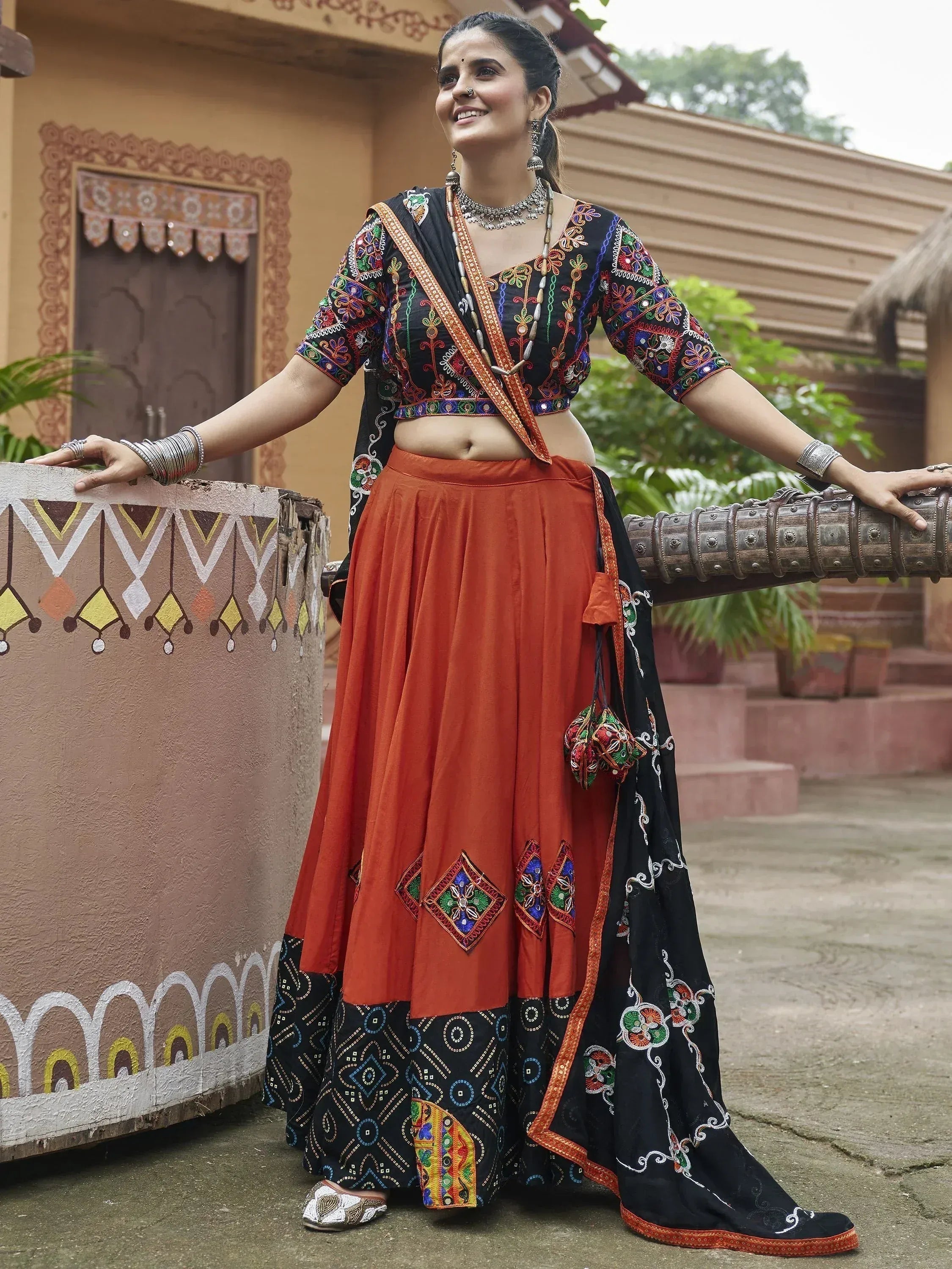 Woman in black and orange embroidered lehenga choli with mirror work, traditional Indian ethnic wear