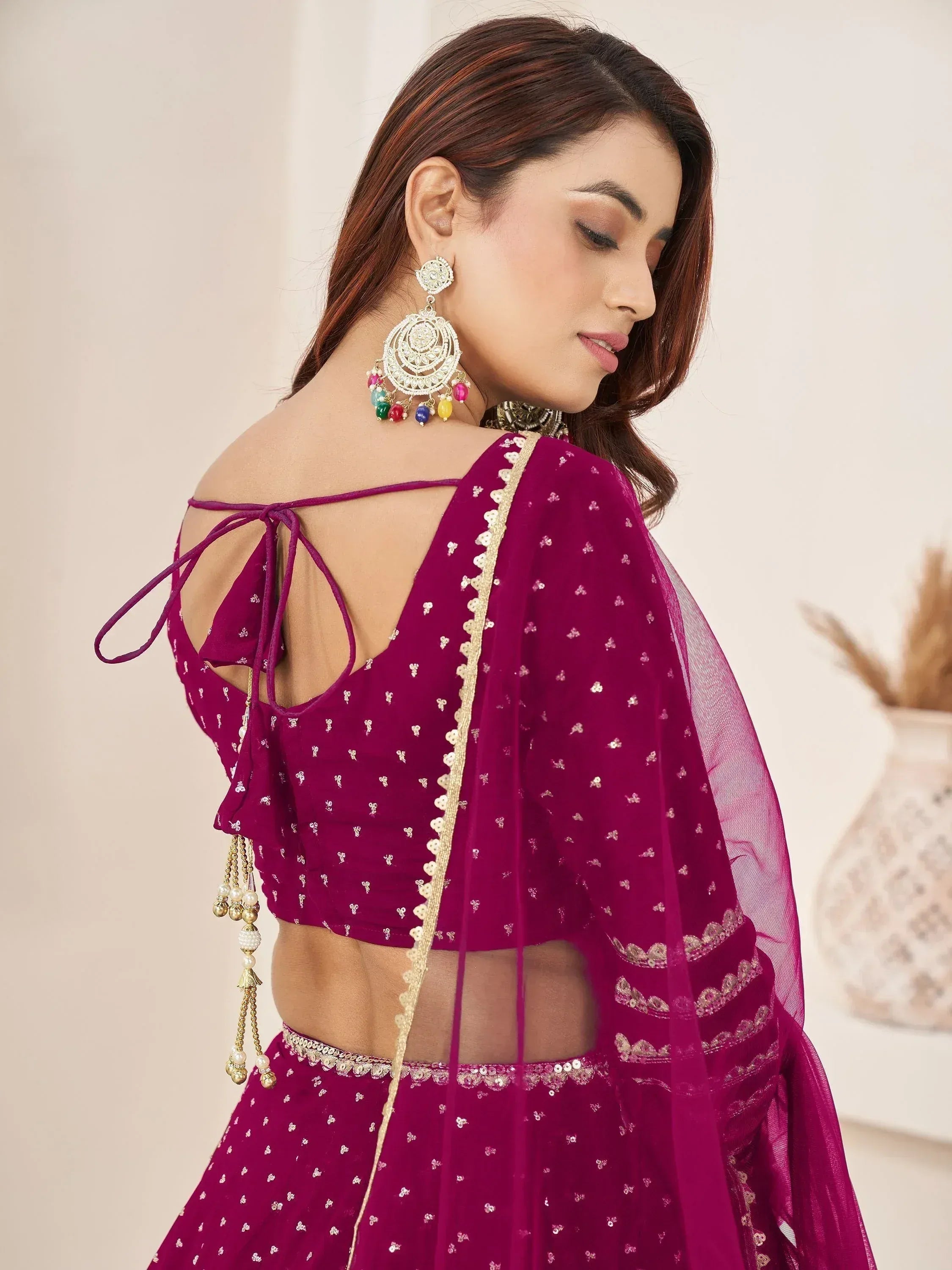 Purple designer lehenga choli with gold embroidery, back tie blouse, and colorful earrings