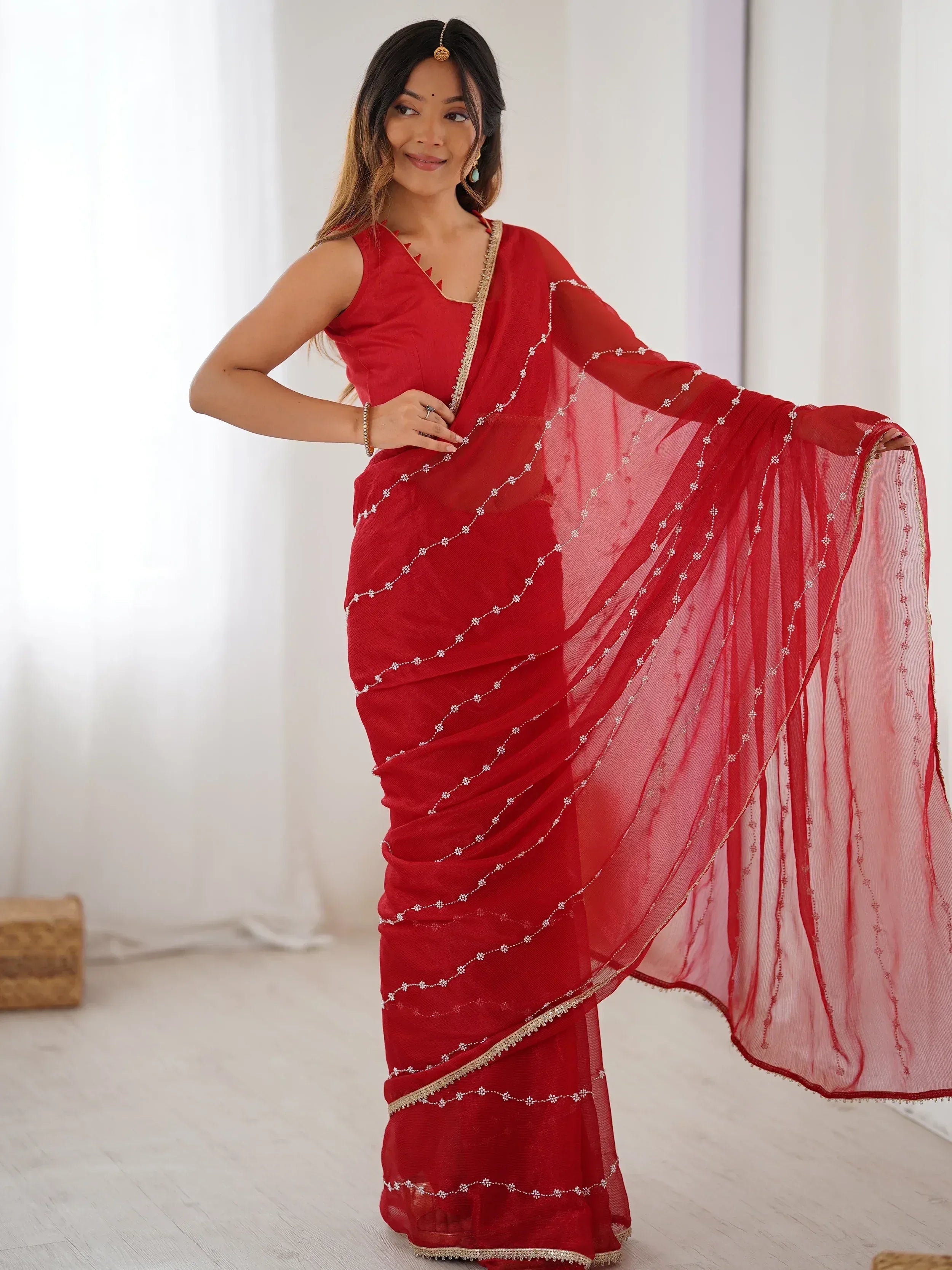 Red embroidered saree with gold trim, styled with matching blouse and traditional jewelry for Indian ethnic wear