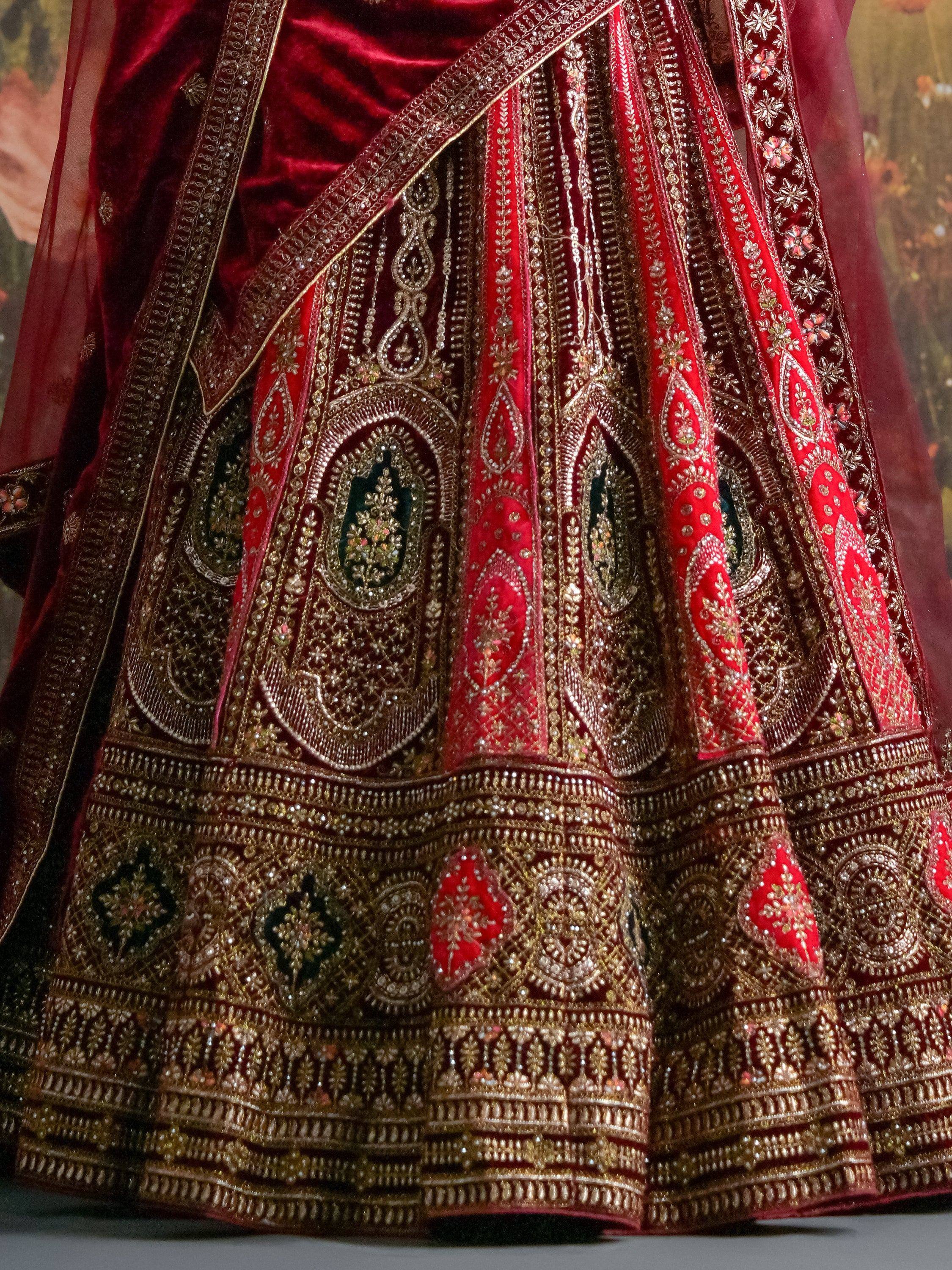 Richly embroidered red velvet lehenga with gold zari and stone work, perfect for Indian weddings and festive occasions.