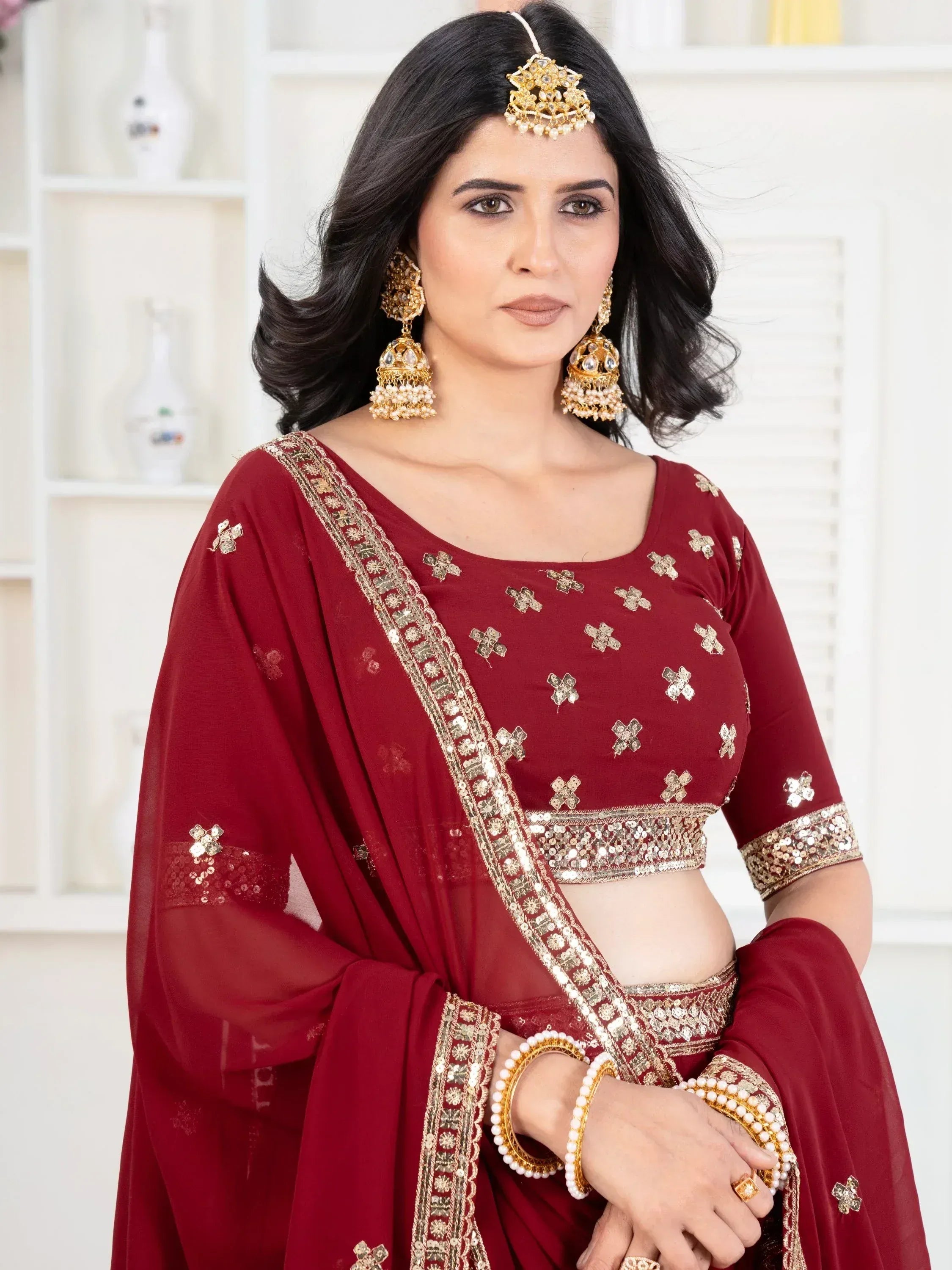 Maroon ethnic lehenga choli with gold embroidery and traditional jewelry for Indian weddings