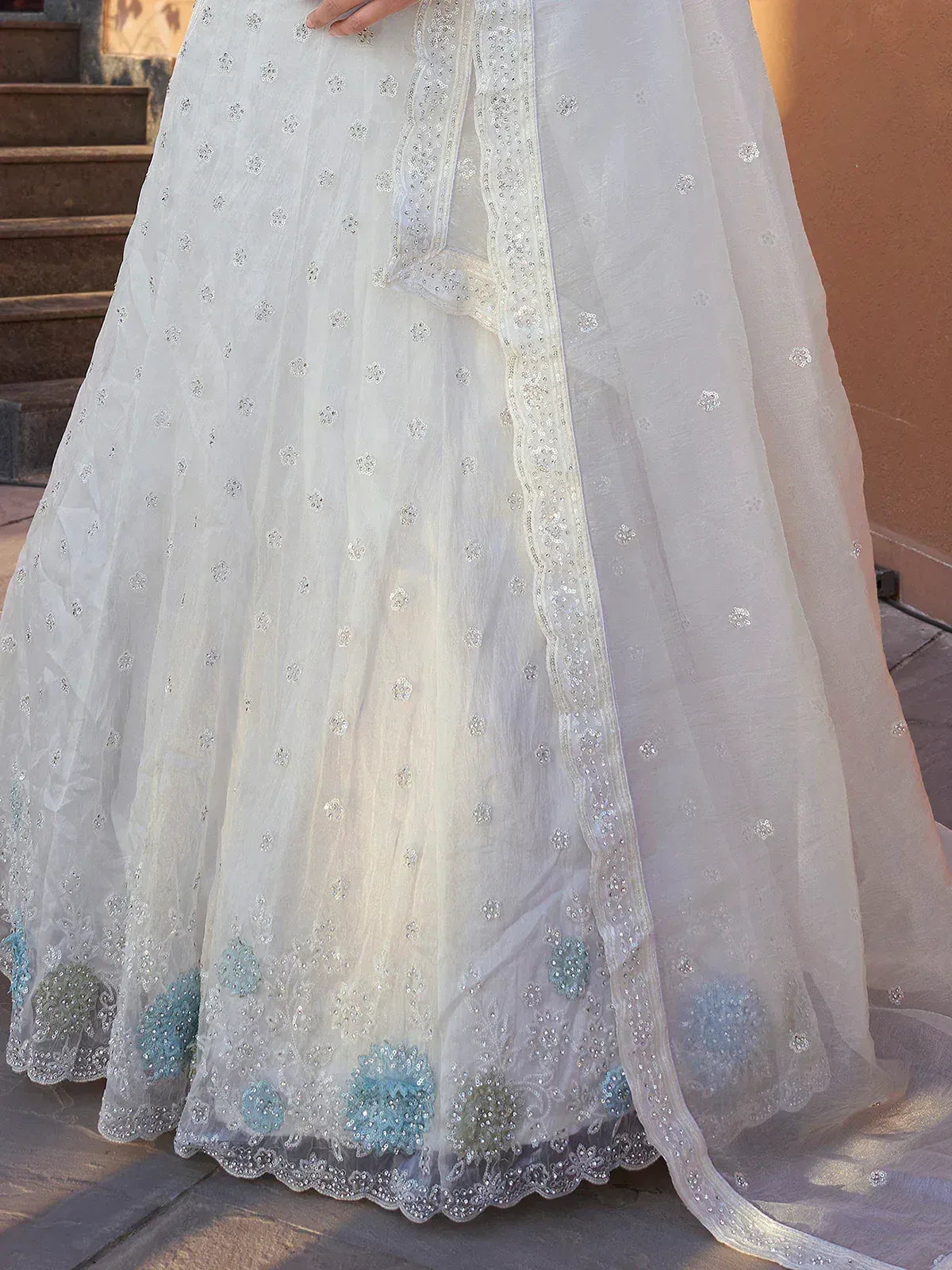 White embroidered lehenga with blue floral motifs and scalloped hem, perfect for Indian ethnic wear