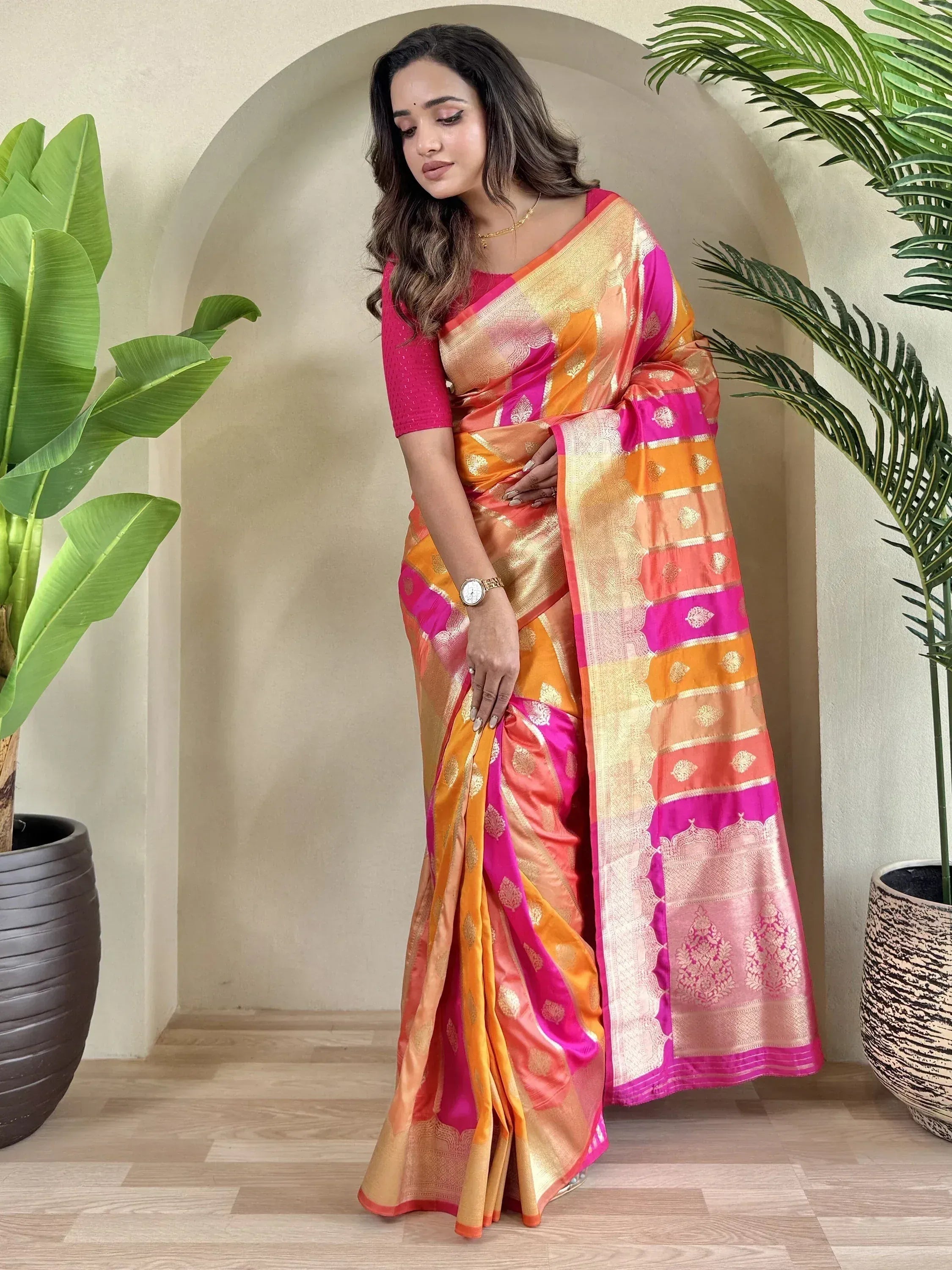 Woman in vibrant pink and orange designer saree with gold zari, perfect for Indian ethnic wear occasions