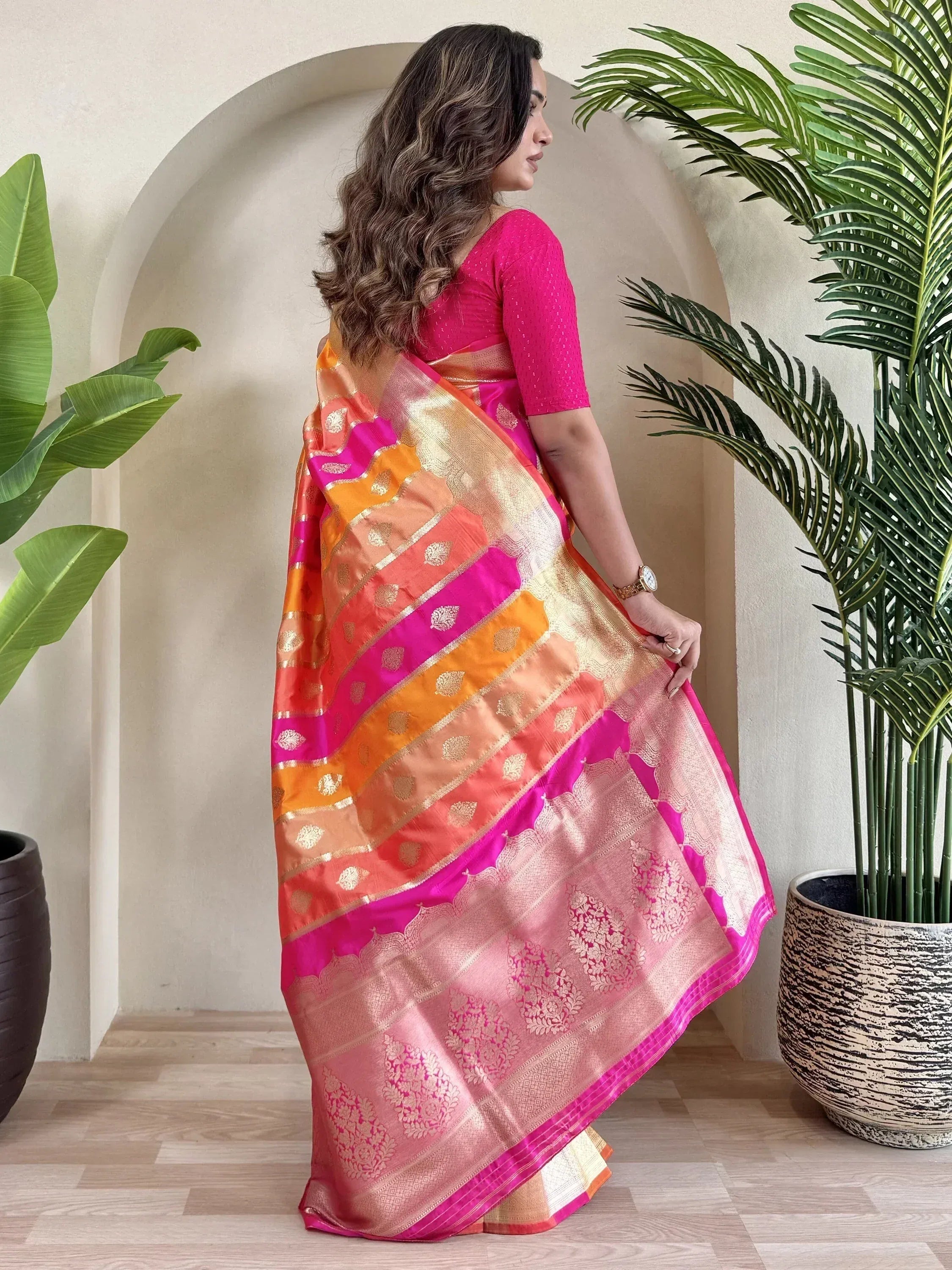 Woman in vibrant pink and orange designer saree with gold zari work, perfect for Indian ethnic wear occasions