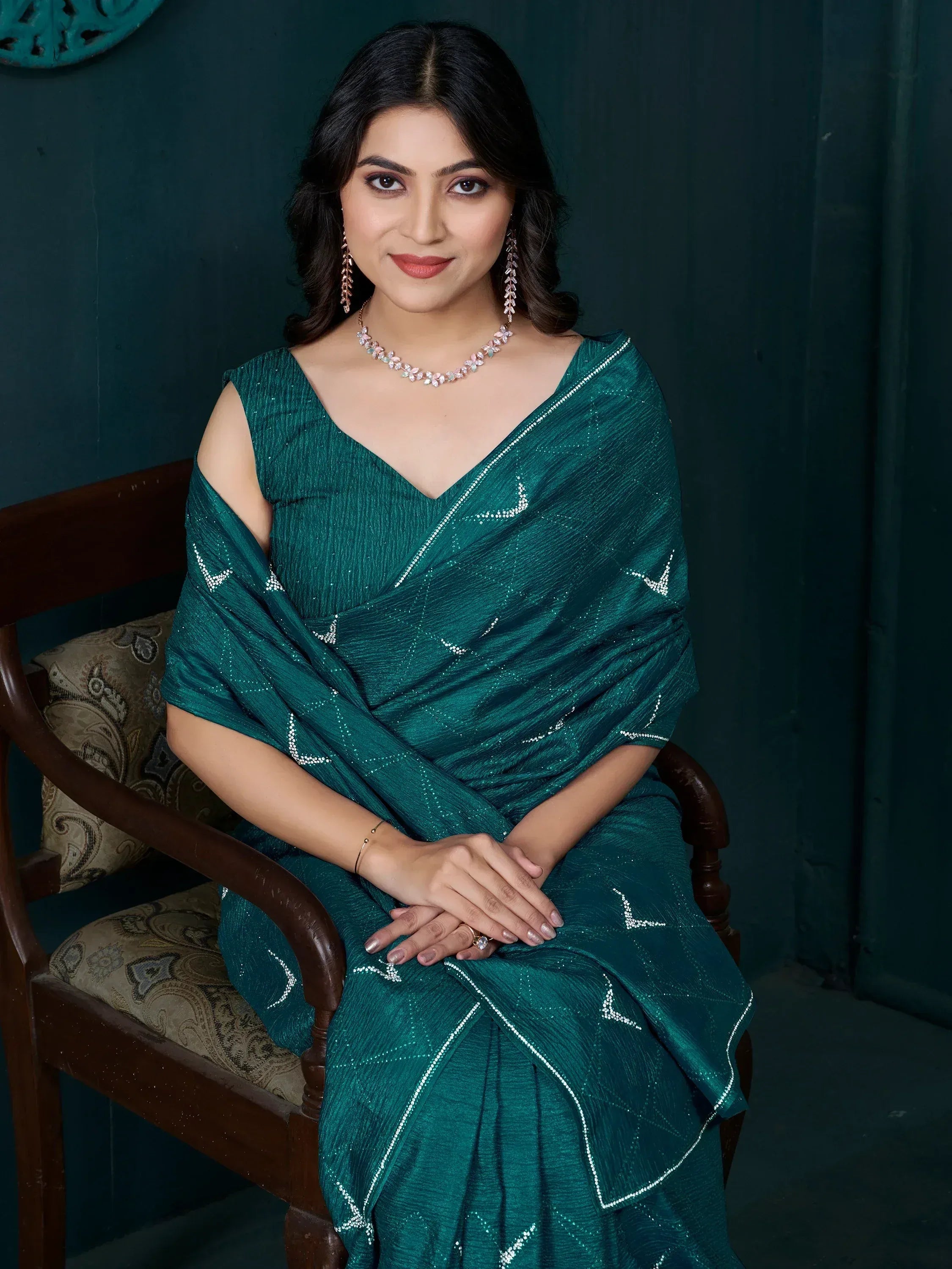 Woman in elegant emerald green saree with silver embellishments, styled for festive occasions