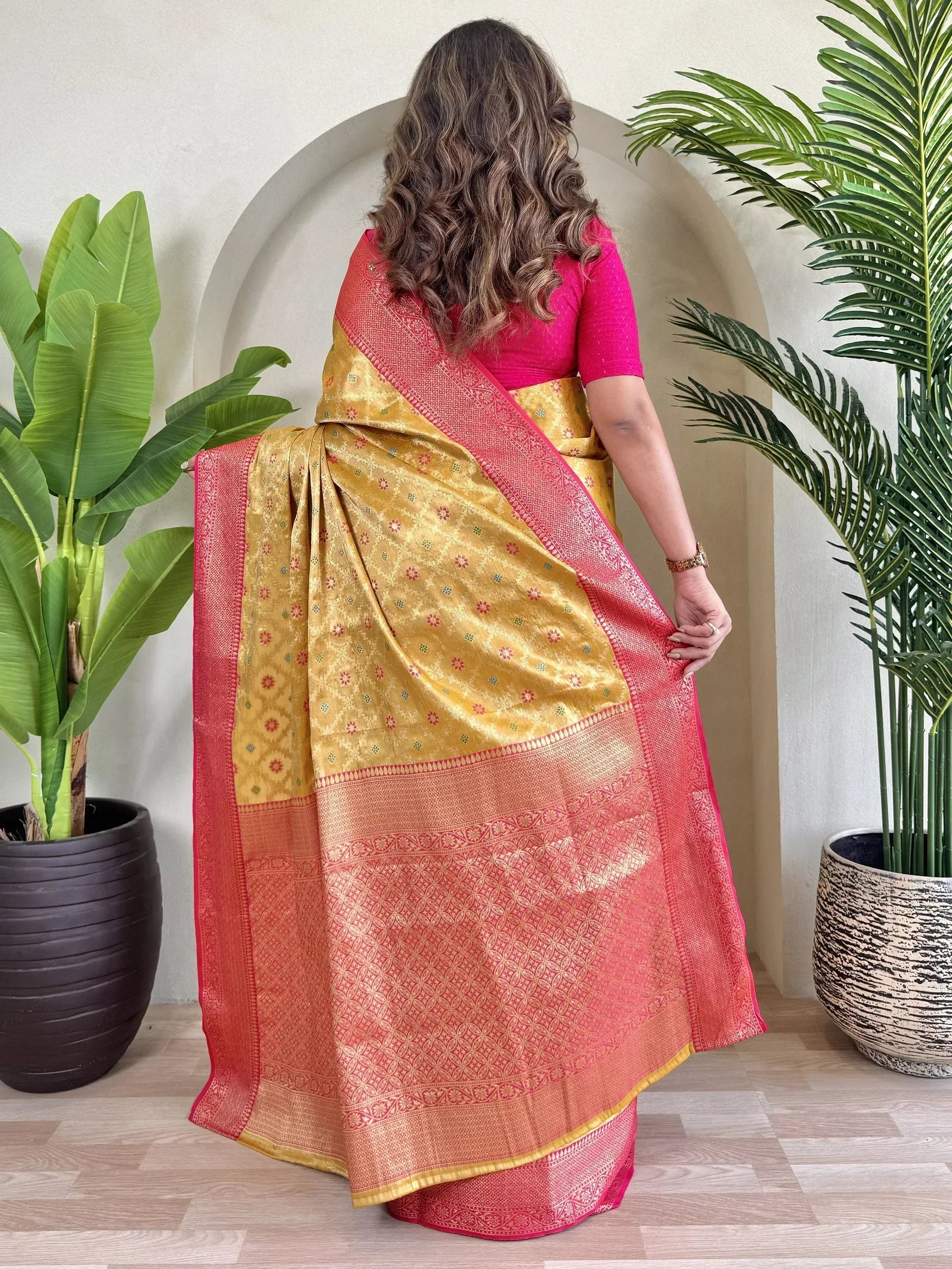 Woman in golden yellow and pink designer saree with intricate floral patterns, perfect for Indian ethnic wear