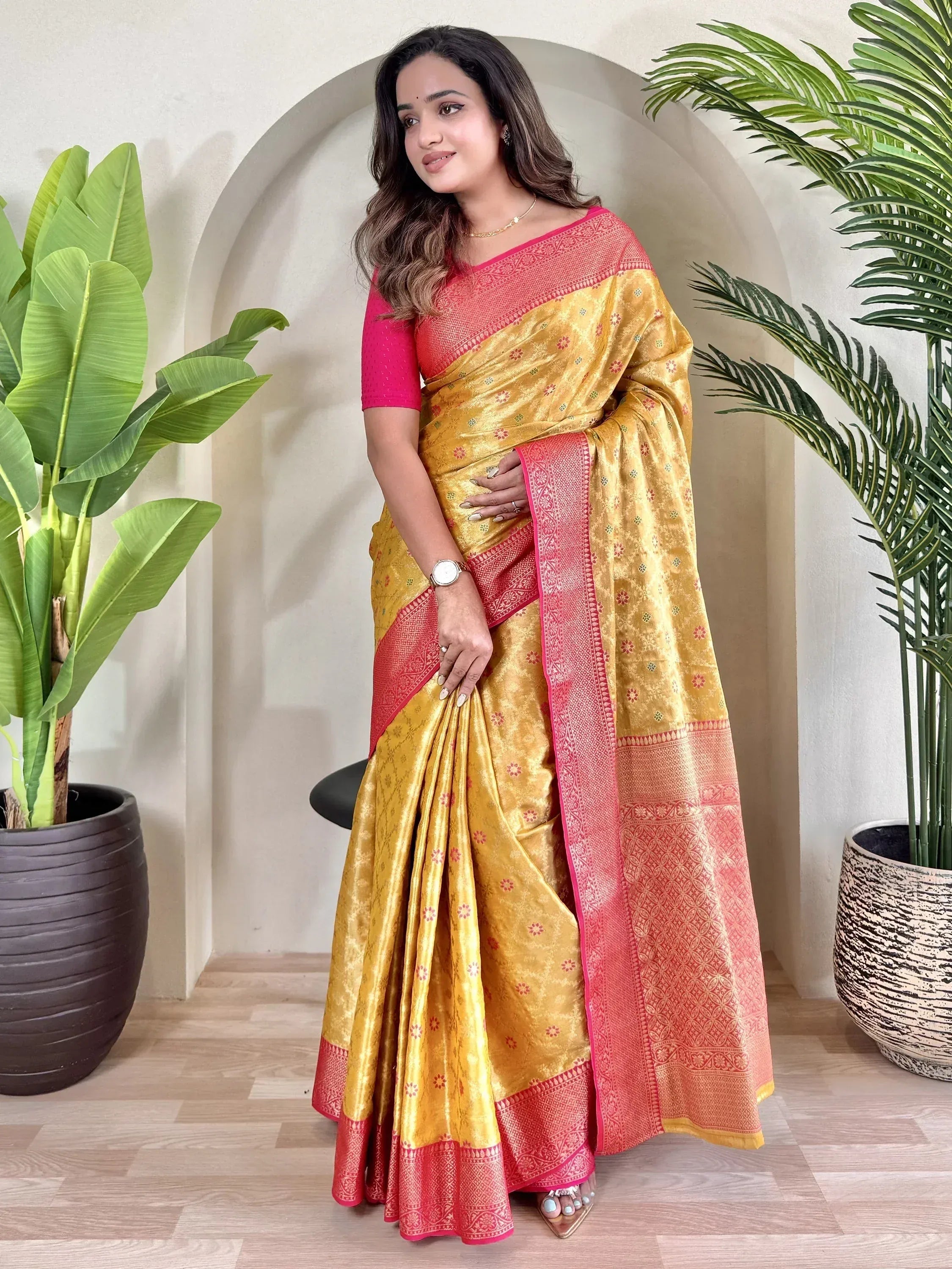 Woman in golden yellow and pink designer saree with intricate border, perfect for ethnic occasions