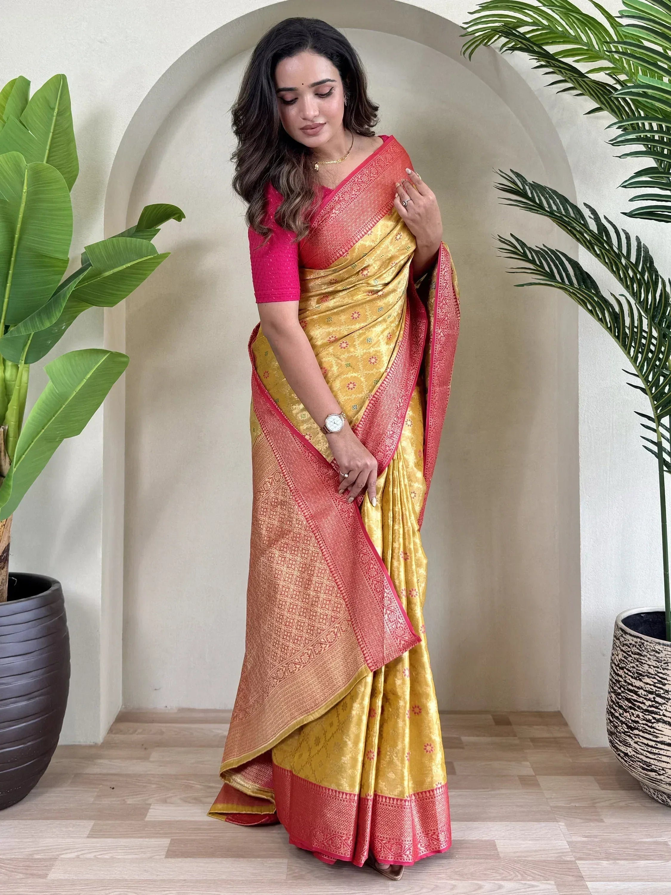 Woman in elegant yellow and pink designer saree with intricate patterns, perfect for ethnic occasions.