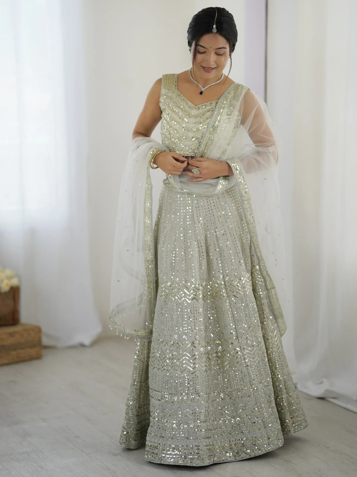 Elegant silver sequin lehenga choli with sheer dupatta, perfect for Indian weddings and festive occasions.