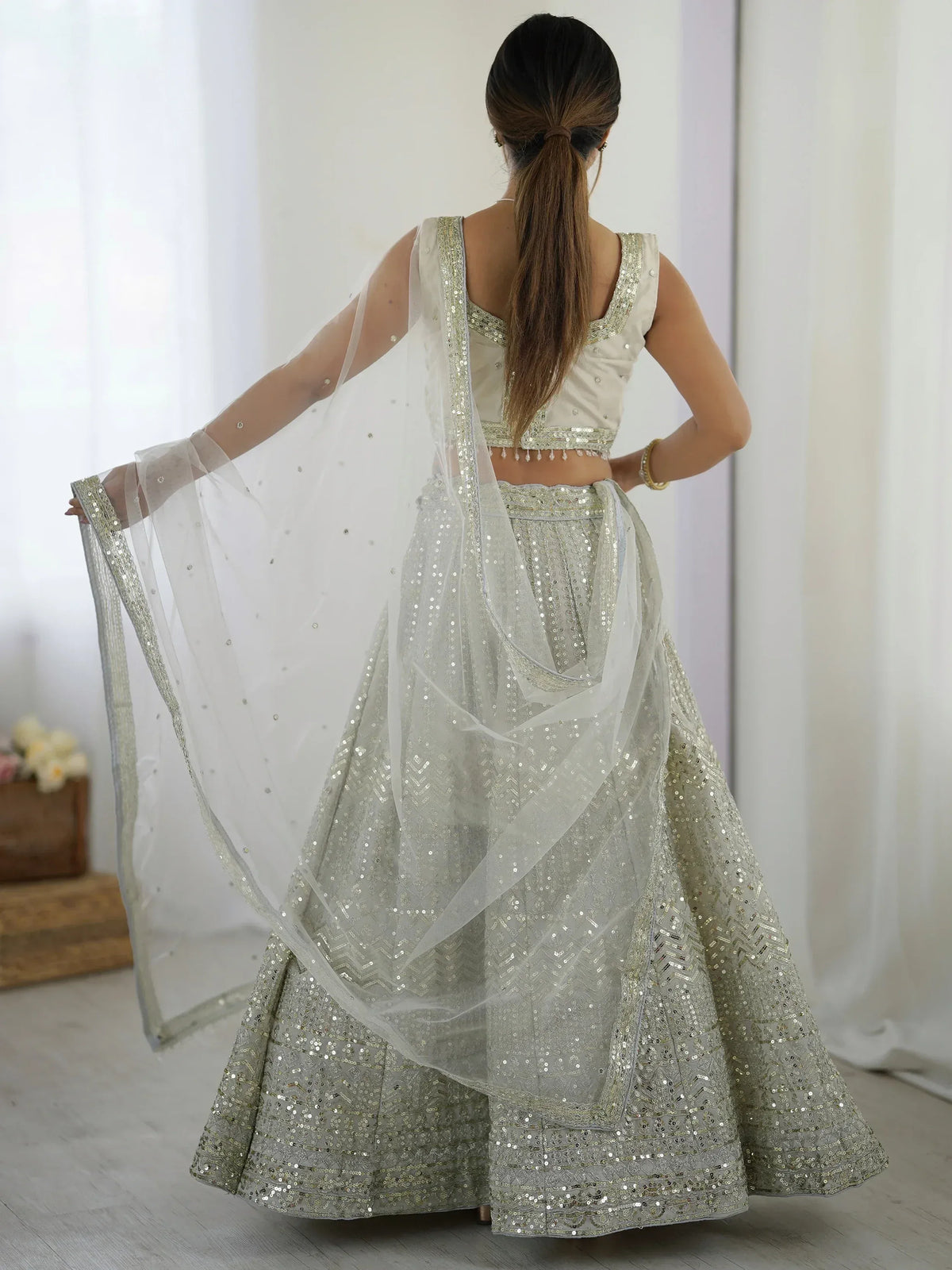Elegant white lehenga choli with gold sequin work, sheer dupatta, perfect for Indian weddings and festive occasions.