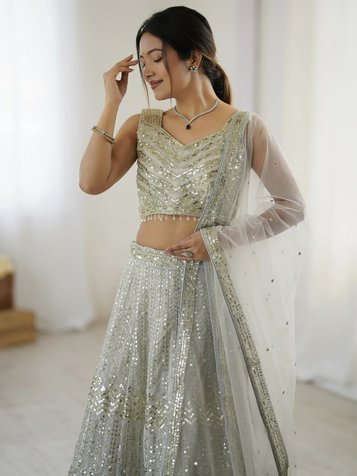 Elegant silver sequin lehenga choli with sheer dupatta, perfect for Indian weddings and festive occasions.