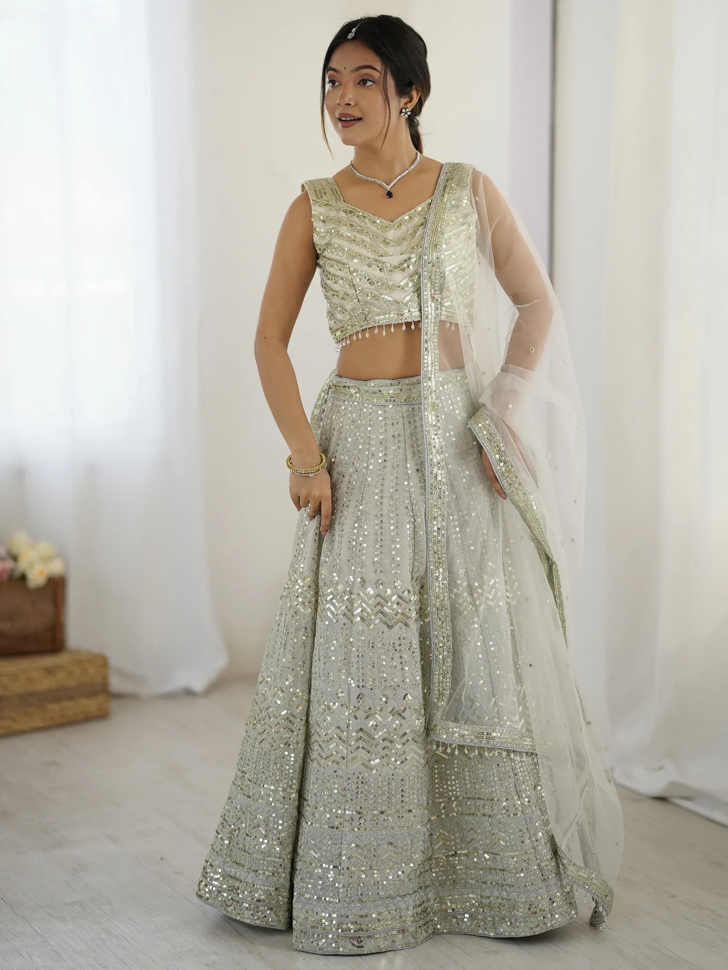 Elegant silver sequin lehenga choli with sheer dupatta, perfect for Indian weddings and festive occasions.