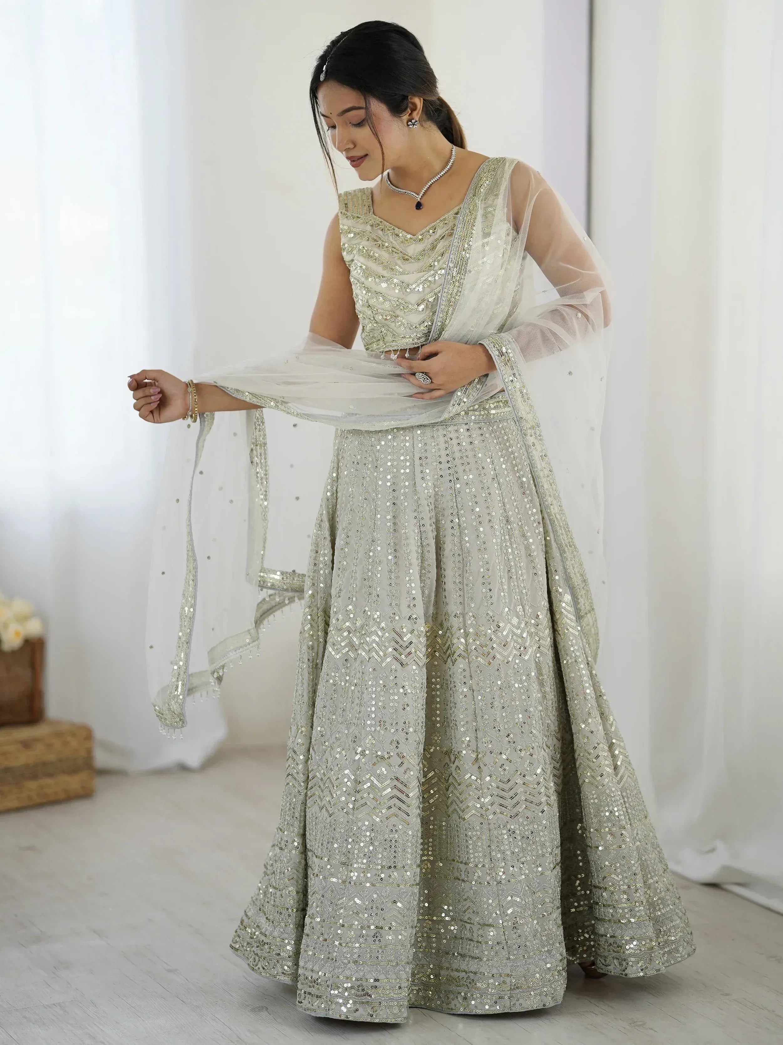 Elegant silver sequin lehenga choli with sheer dupatta, perfect for Indian weddings and festive occasions.