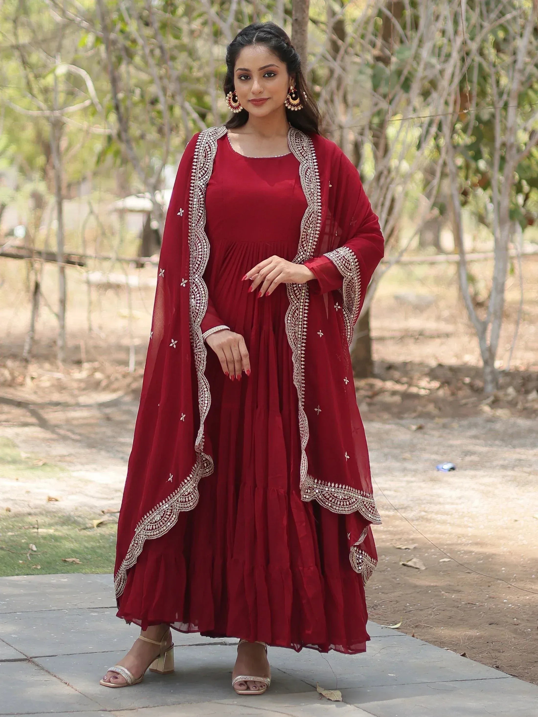 Woman in maroon ethnic gown with embroidered dupatta, outdoor setting, Indian ethnic wear