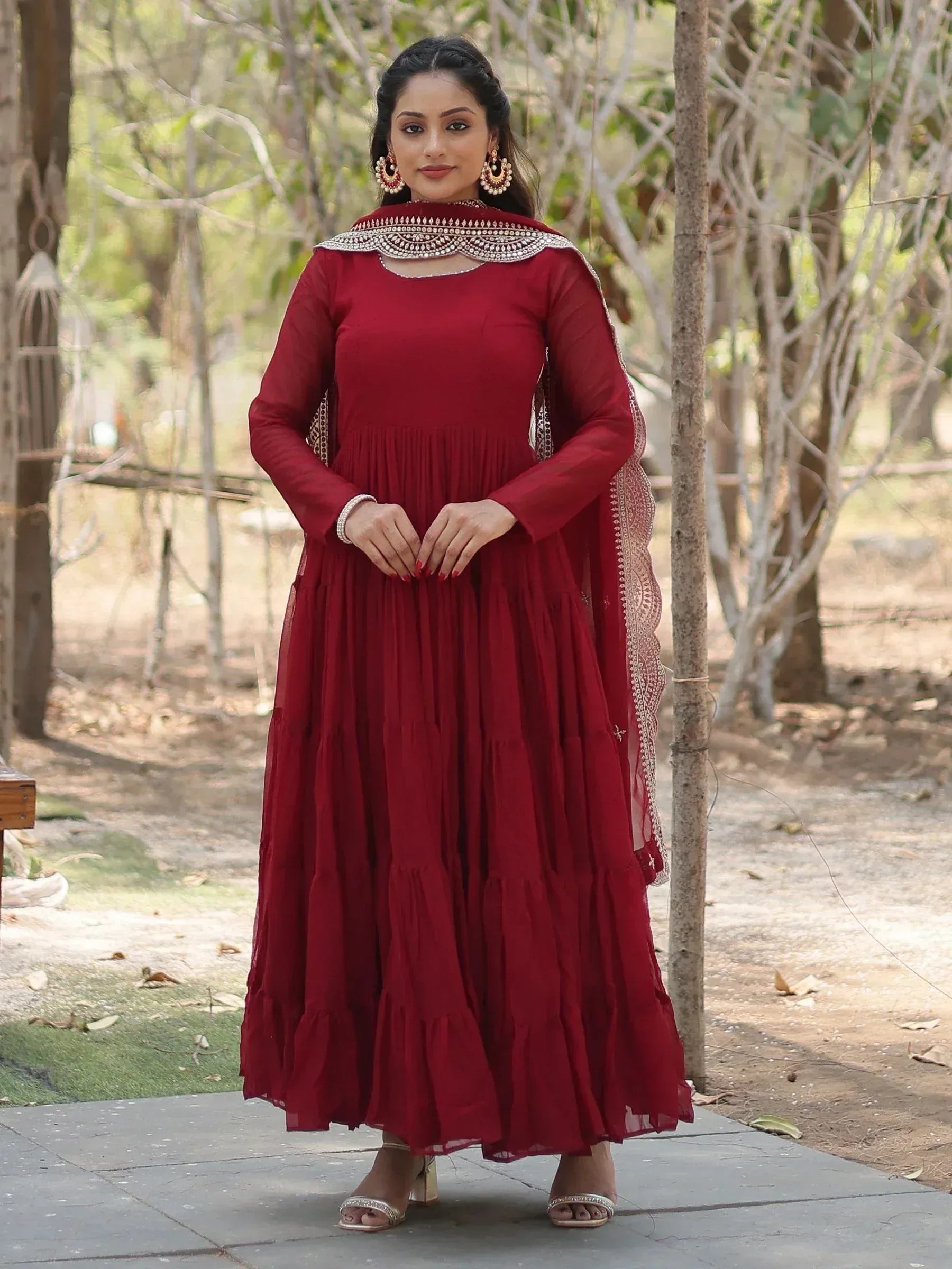 Woman wearing maroon ethnic gown with dupatta in outdoor garden setting