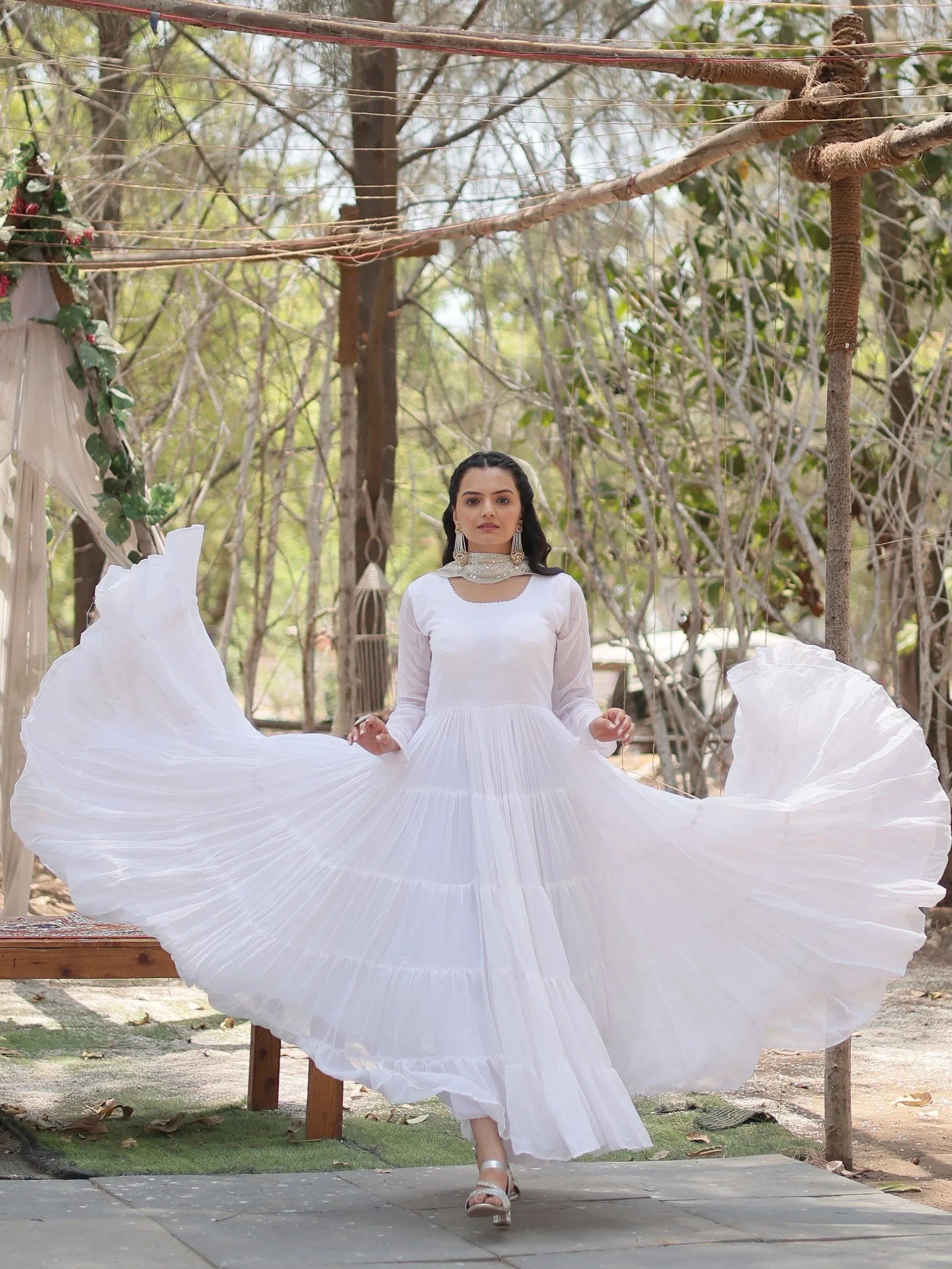 Woman wearing a flowing long white ethnic gown with flared sleeves, outdoors in daylight