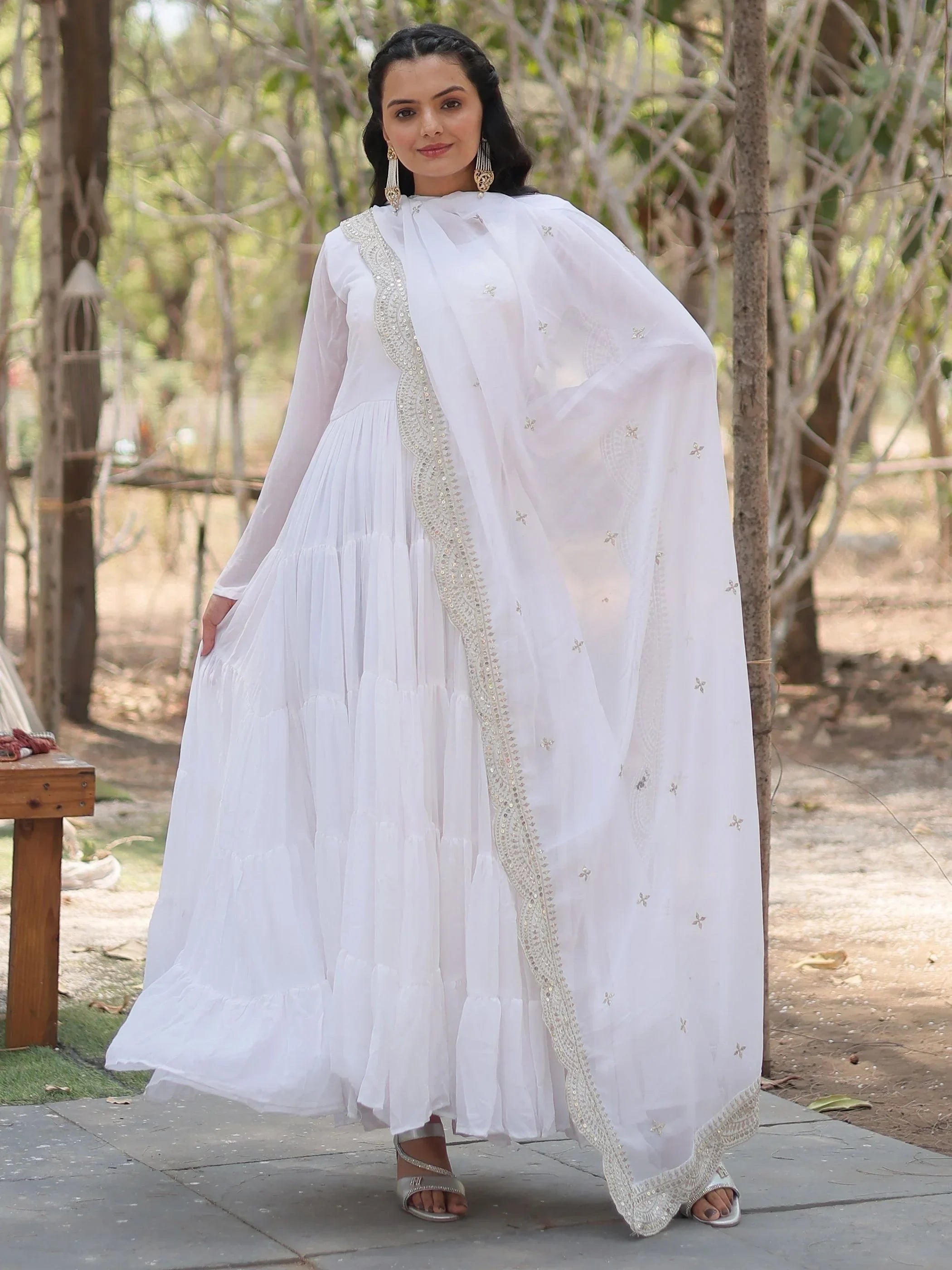 Woman wearing white Indian ethnic gown with dupatta and gold embroidery outdoors