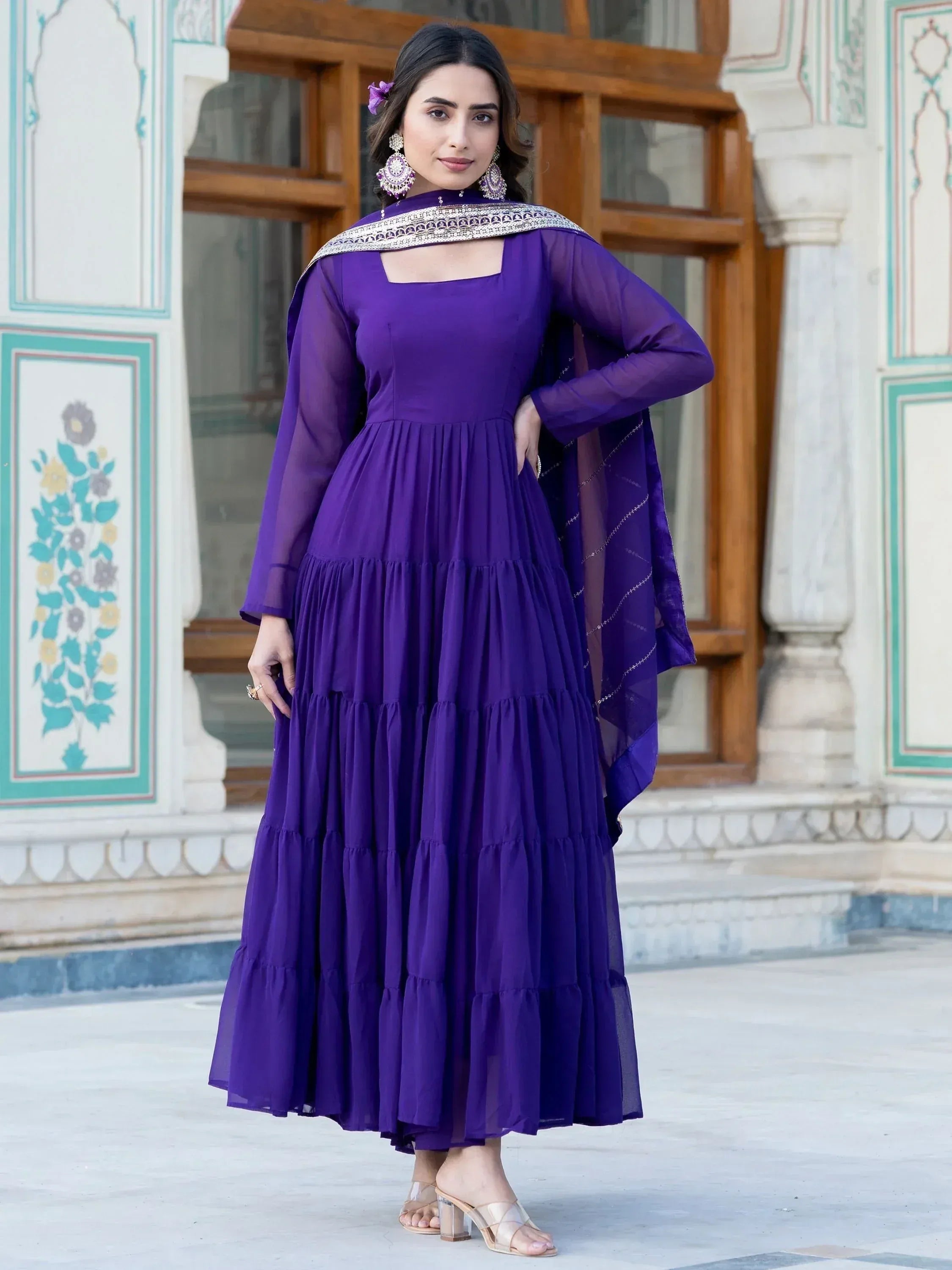 Purple tiered ethnic gown with sheer sleeves and embroidered dupatta, perfect for Indian occasions.