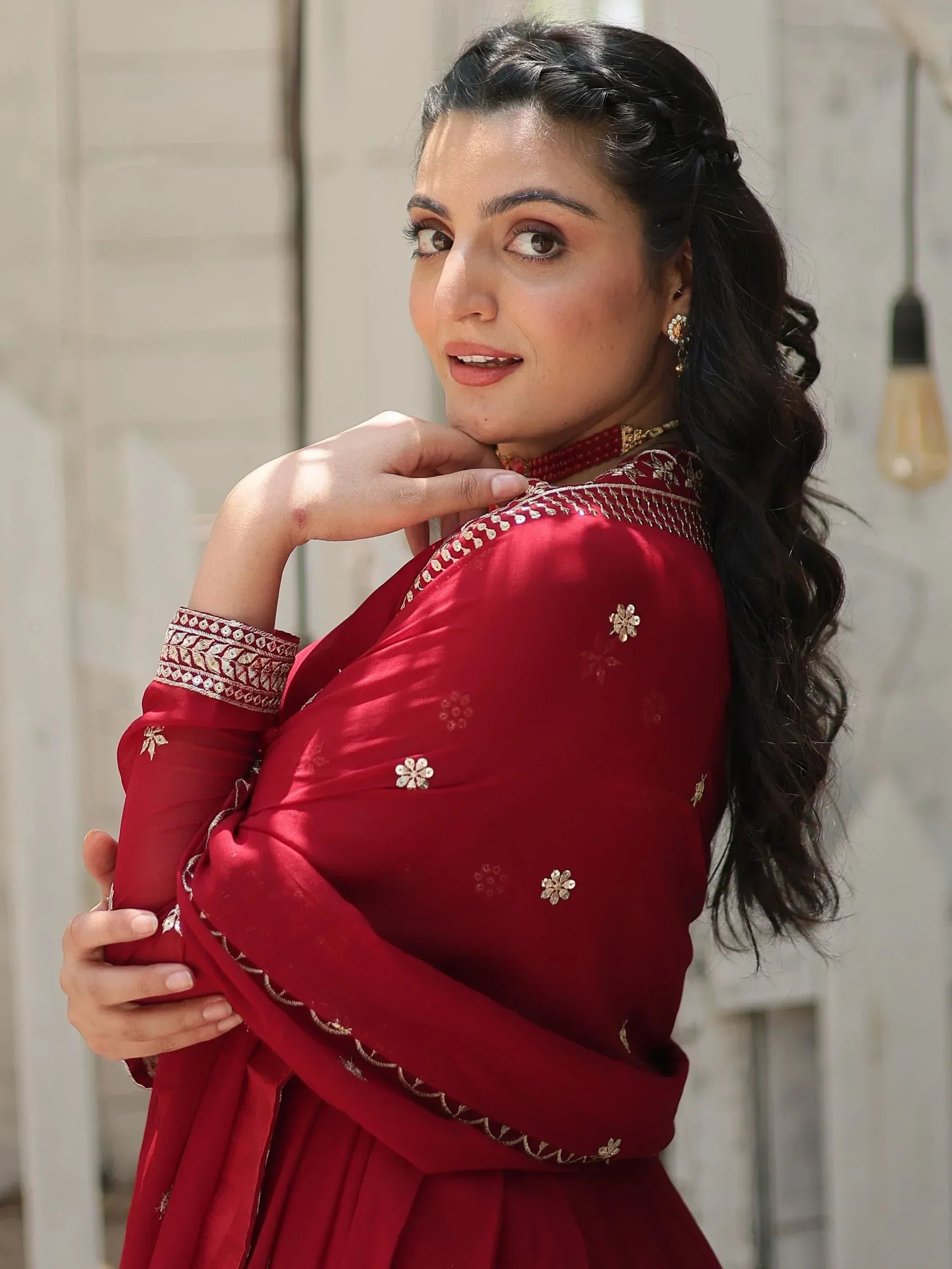 Woman in maroon embroidered ethnic gown with gold detailing, perfect for Indian festive occasions