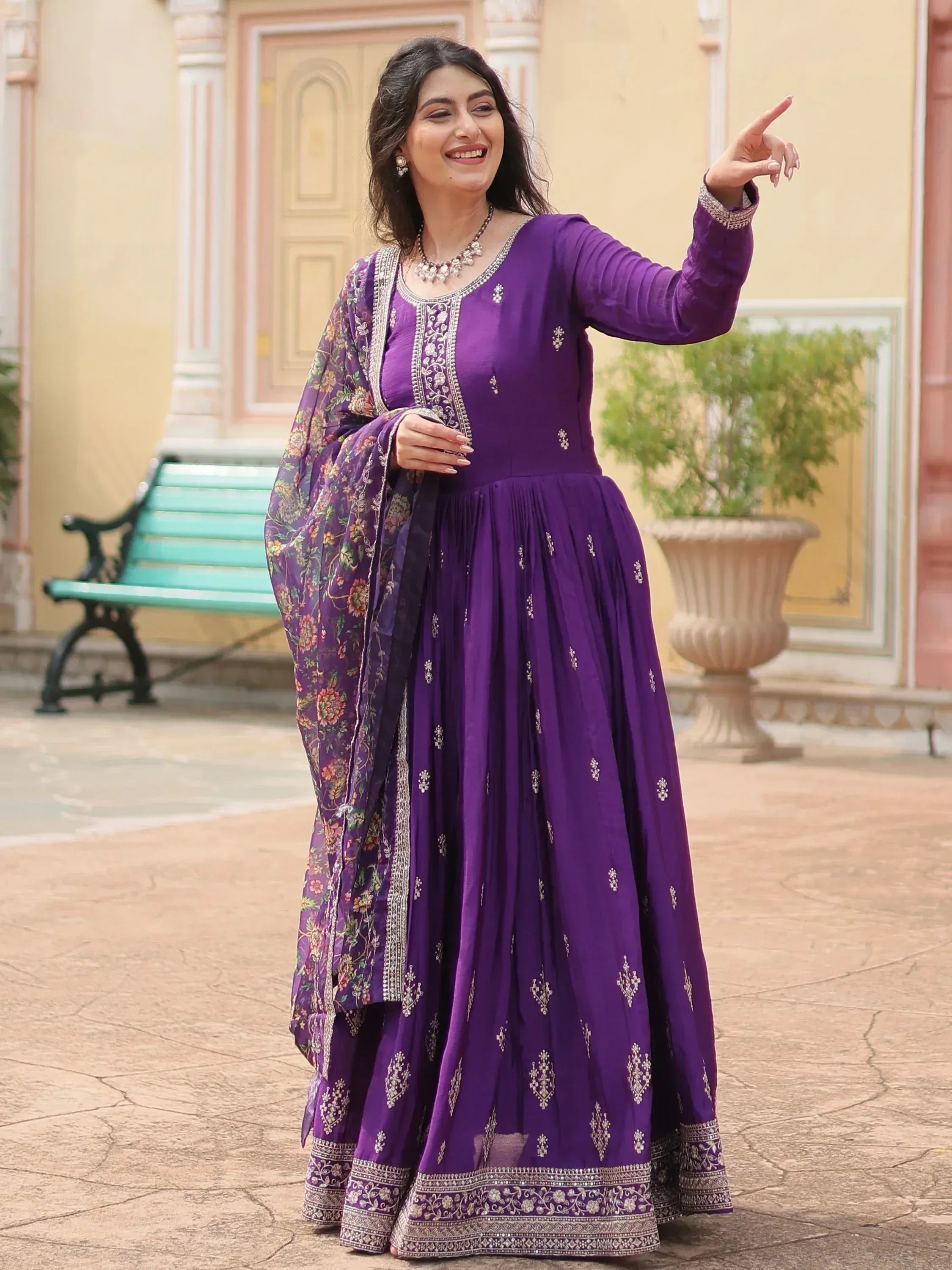 Woman wearing a purple embroidered ethnic gown with matching dupatta outdoors