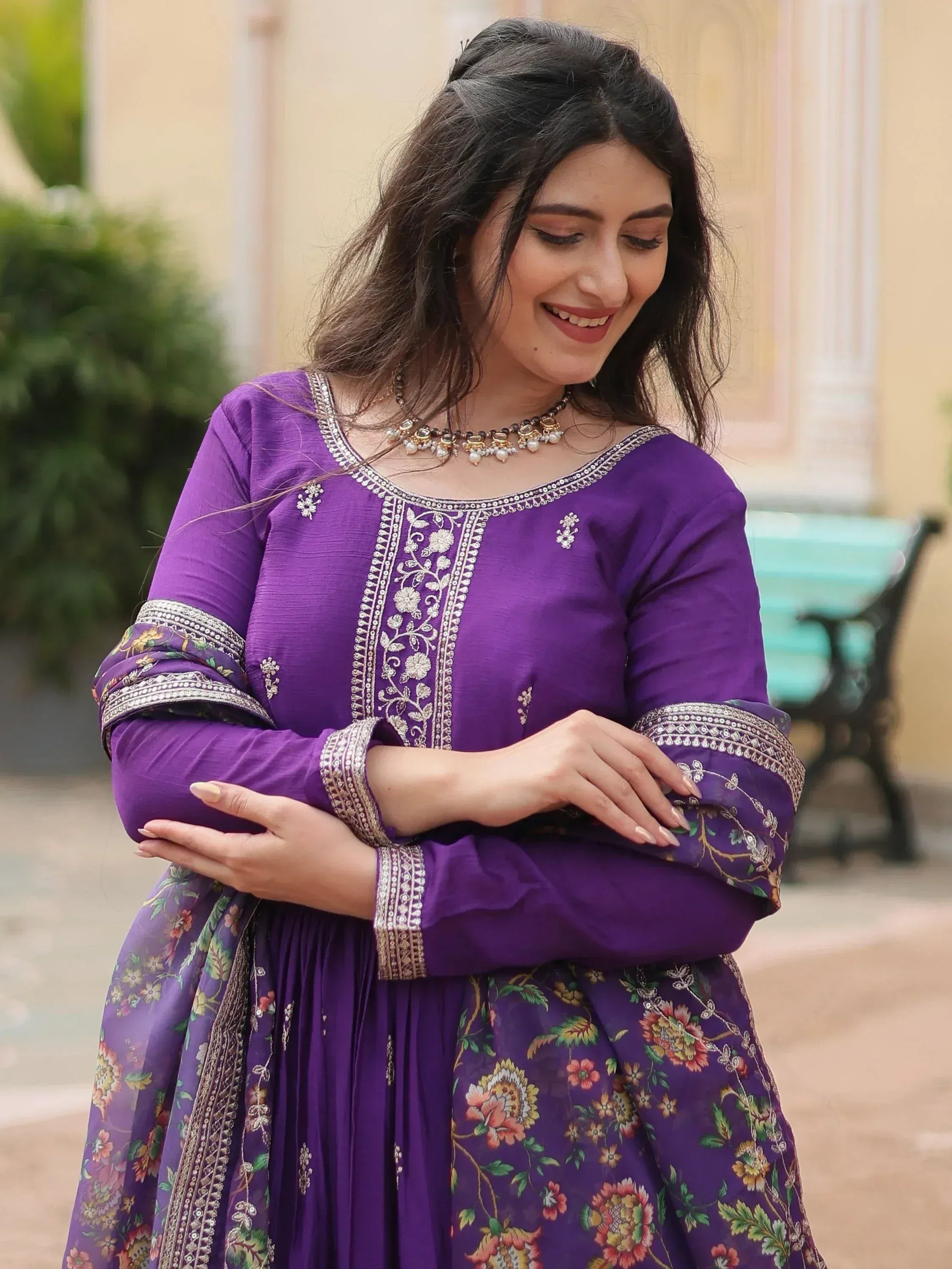 Woman in a purple ethnic gown with floral dupatta and silver embroidery, smiling outdoors