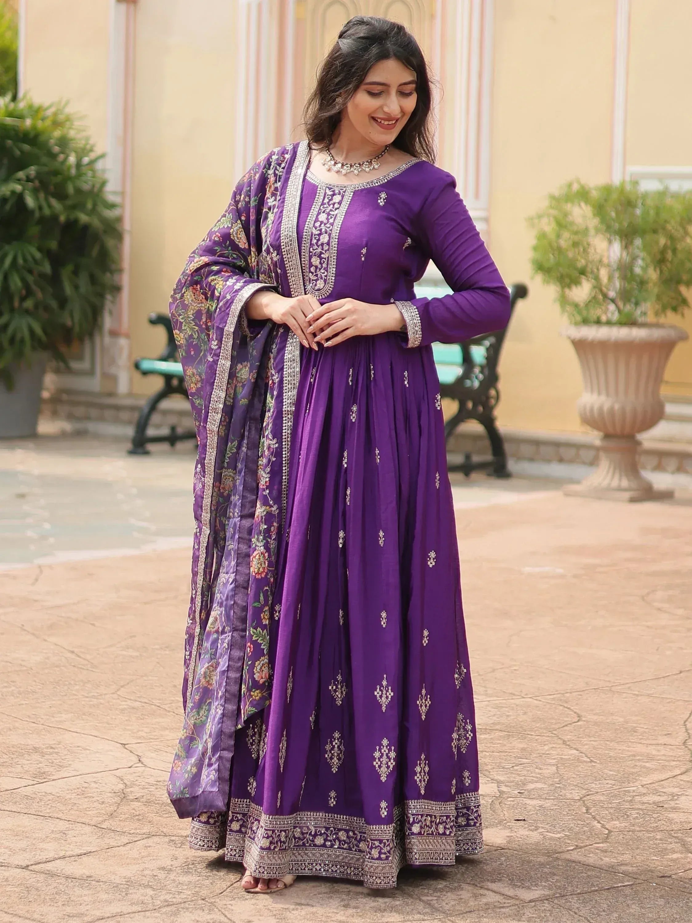 Woman wearing a purple embroidered Anarkali suit with floral dupatta, traditional Indian ethnic wear