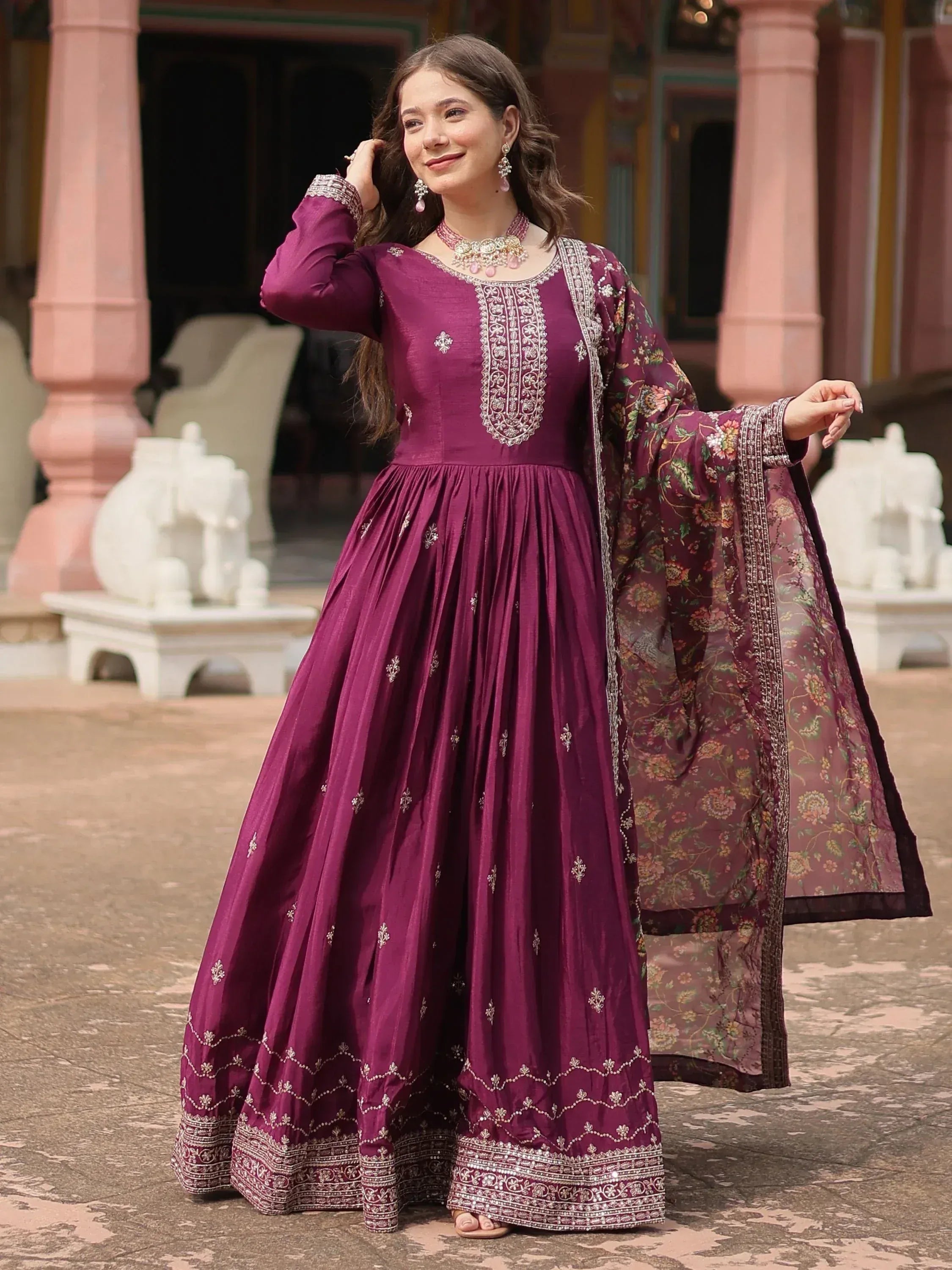 Woman in wine-colored embroidered Anarkali gown with dupatta, ethnic Indian attire outdoors
