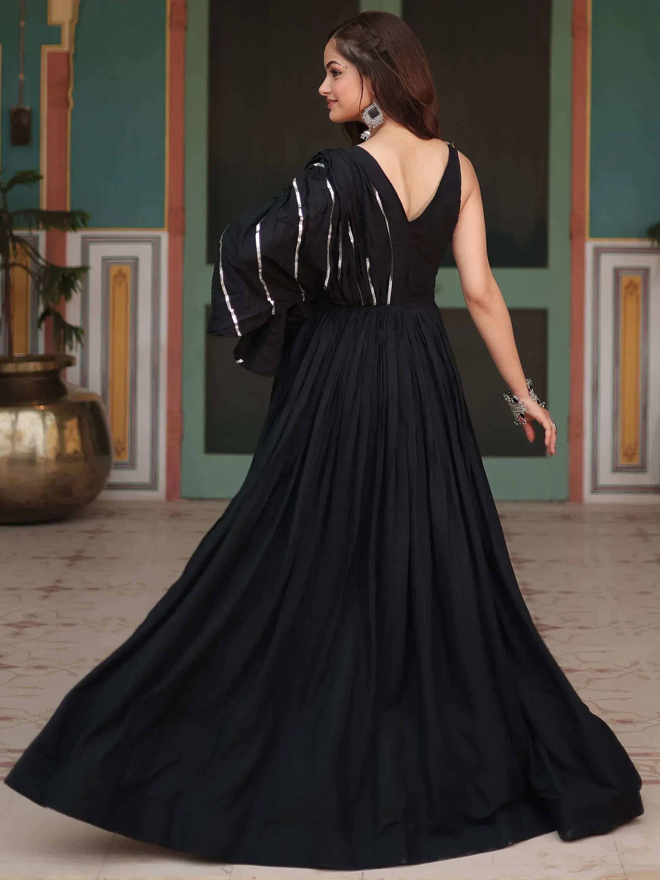 Woman wearing a black ethnic gown with silver accents, posing indoors