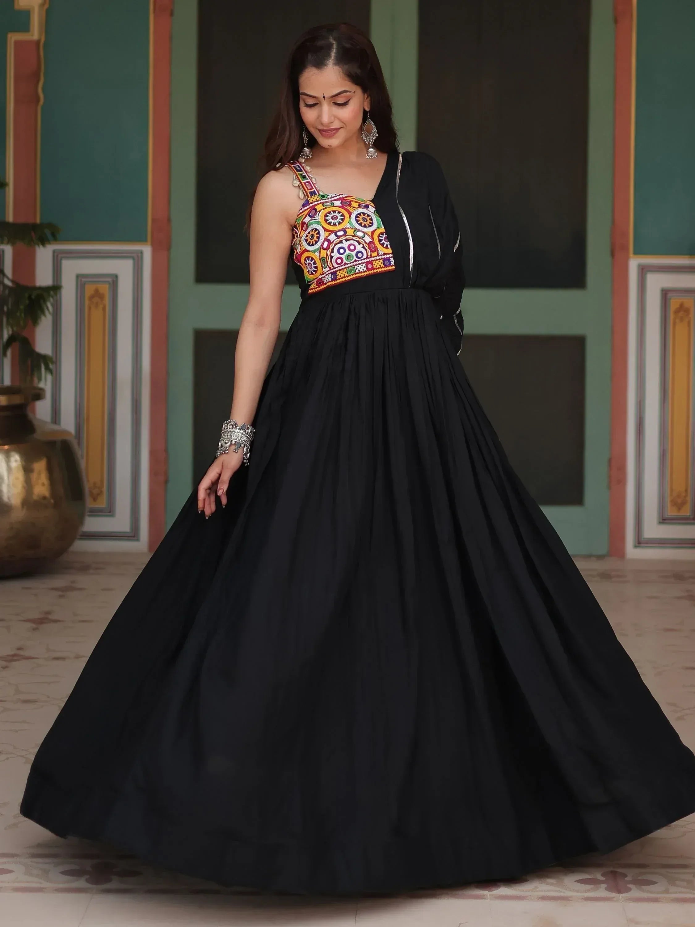 Woman wearing black ethnic gown with colorful embroidered bodice, traditional Indian jewelry
