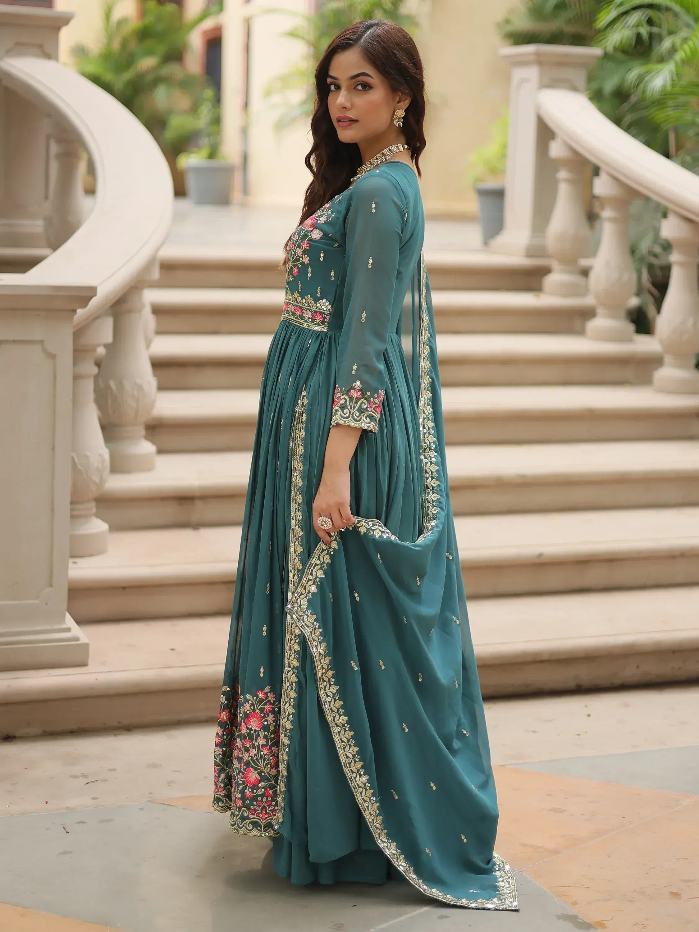 Teal ethnic gown with floral embroidery and gold detailing, perfect for Indian weddings or festive occasions.