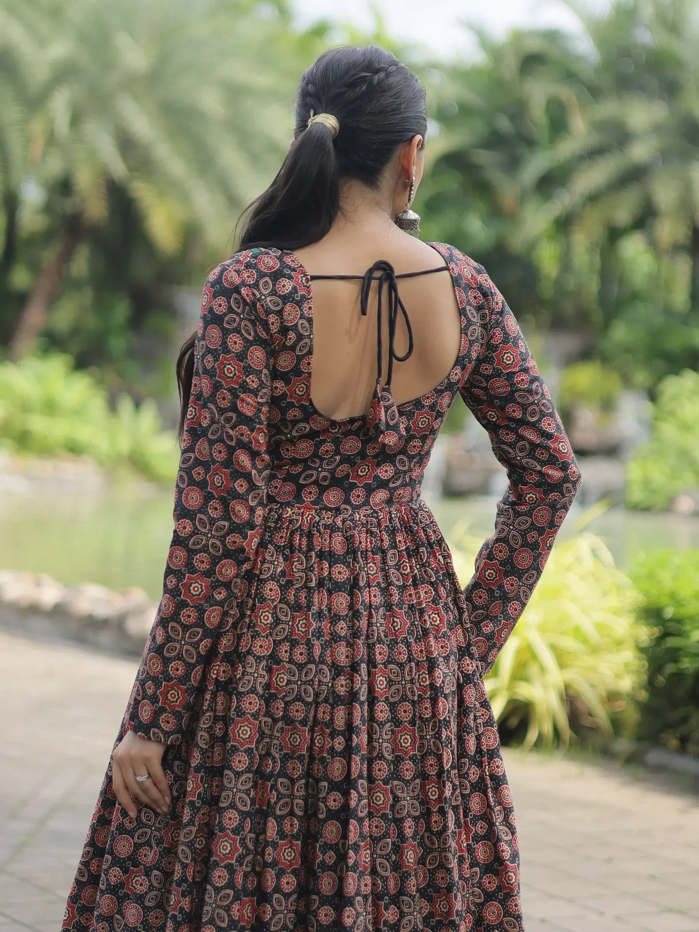 Woman in black and red printed ethnic gown with open back tie, walking outdoors