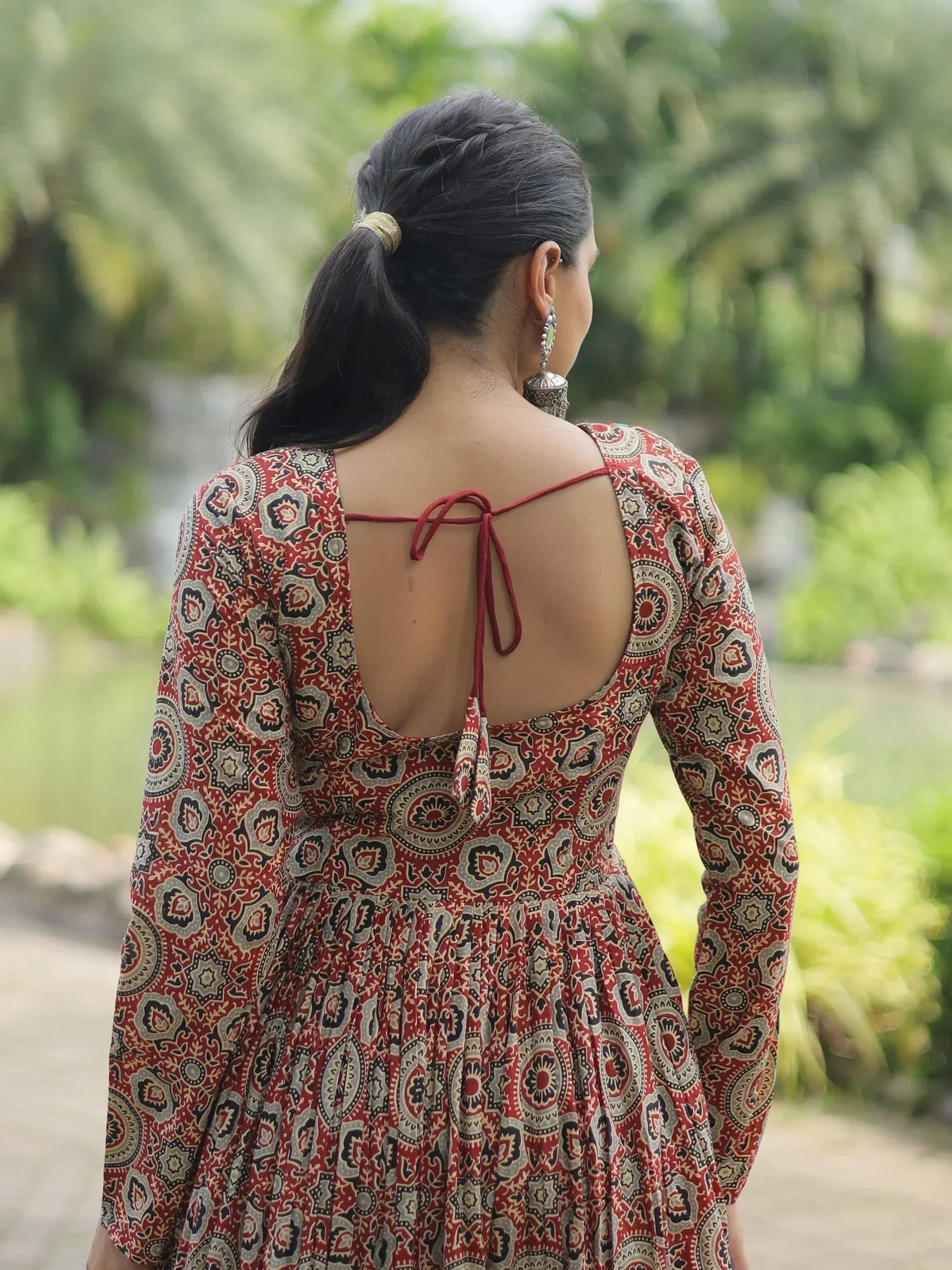 Woman in red ethnic print gown with back tie detail, perfect for Indian occasions