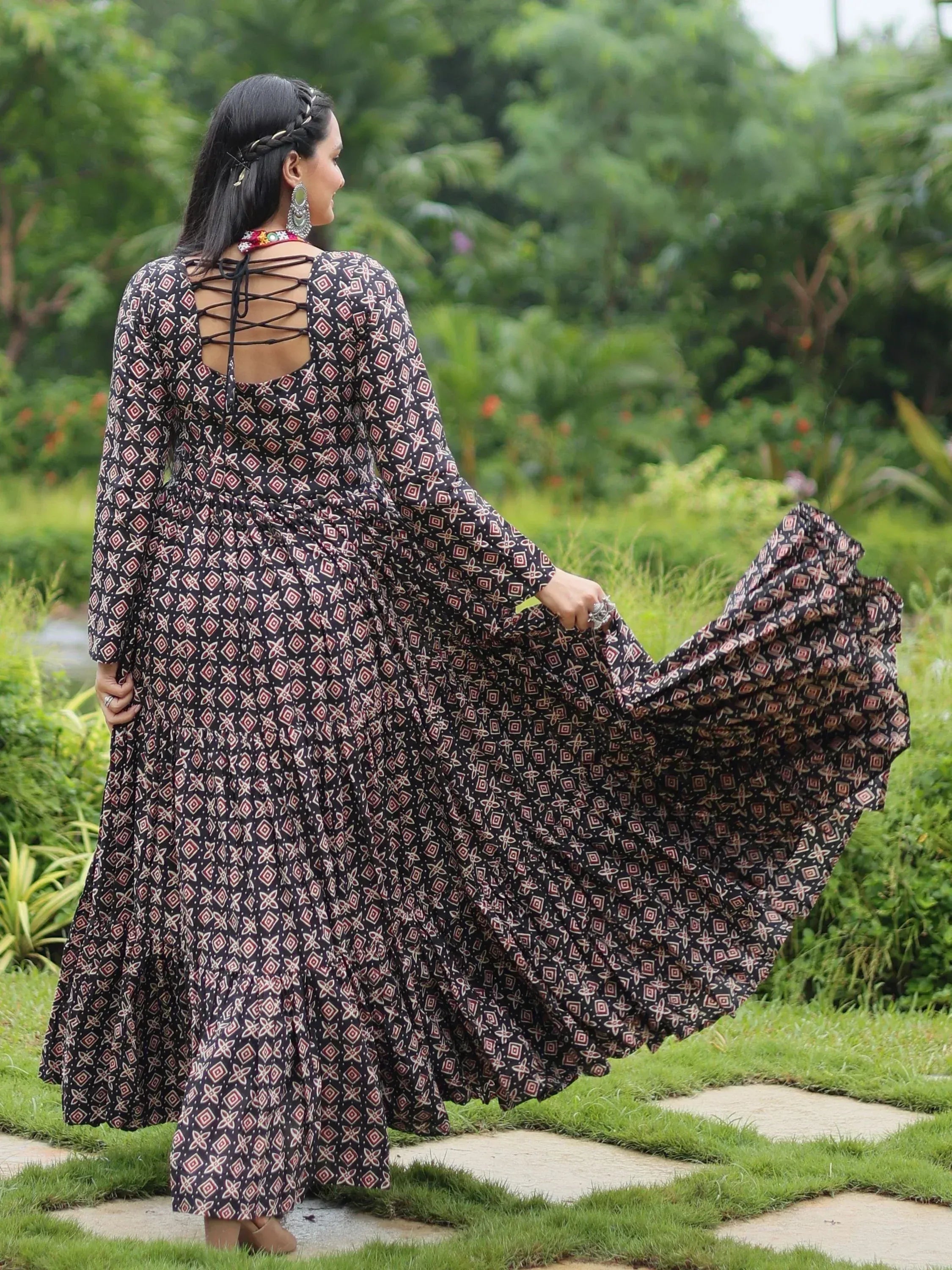 Woman in black printed ethnic gown with crisscross back, walking in garden