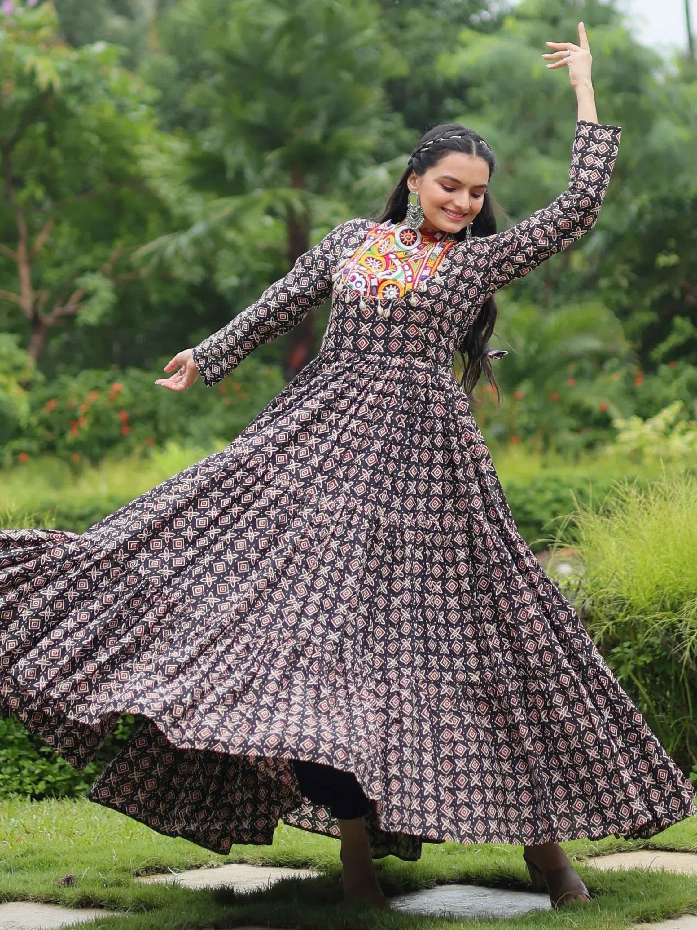 Woman twirling in black printed ethnic gown with colorful embroidery, perfect for Indian festive wear.
