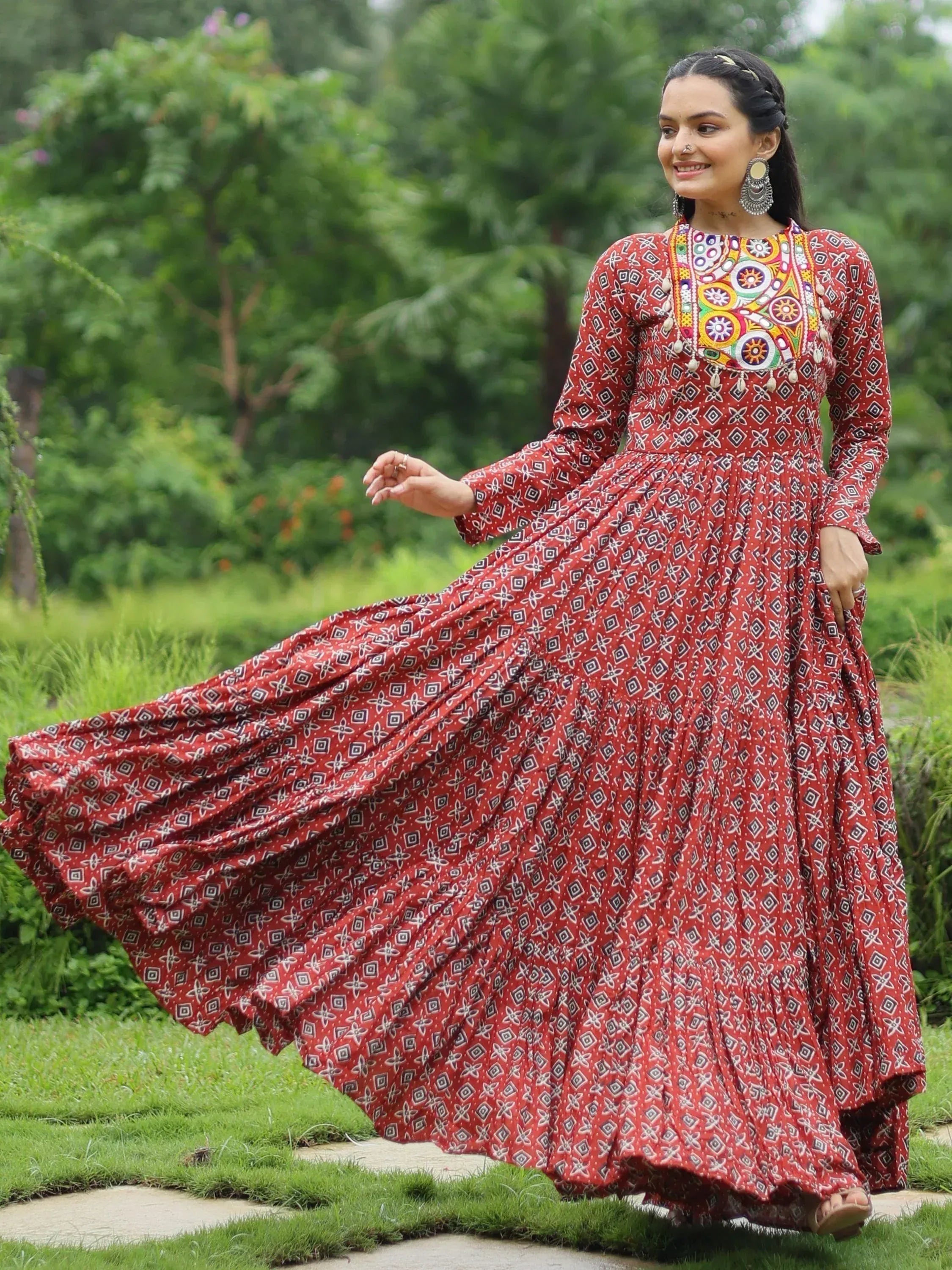 Woman in red printed ethnic gown with mirror work, walking in garden
