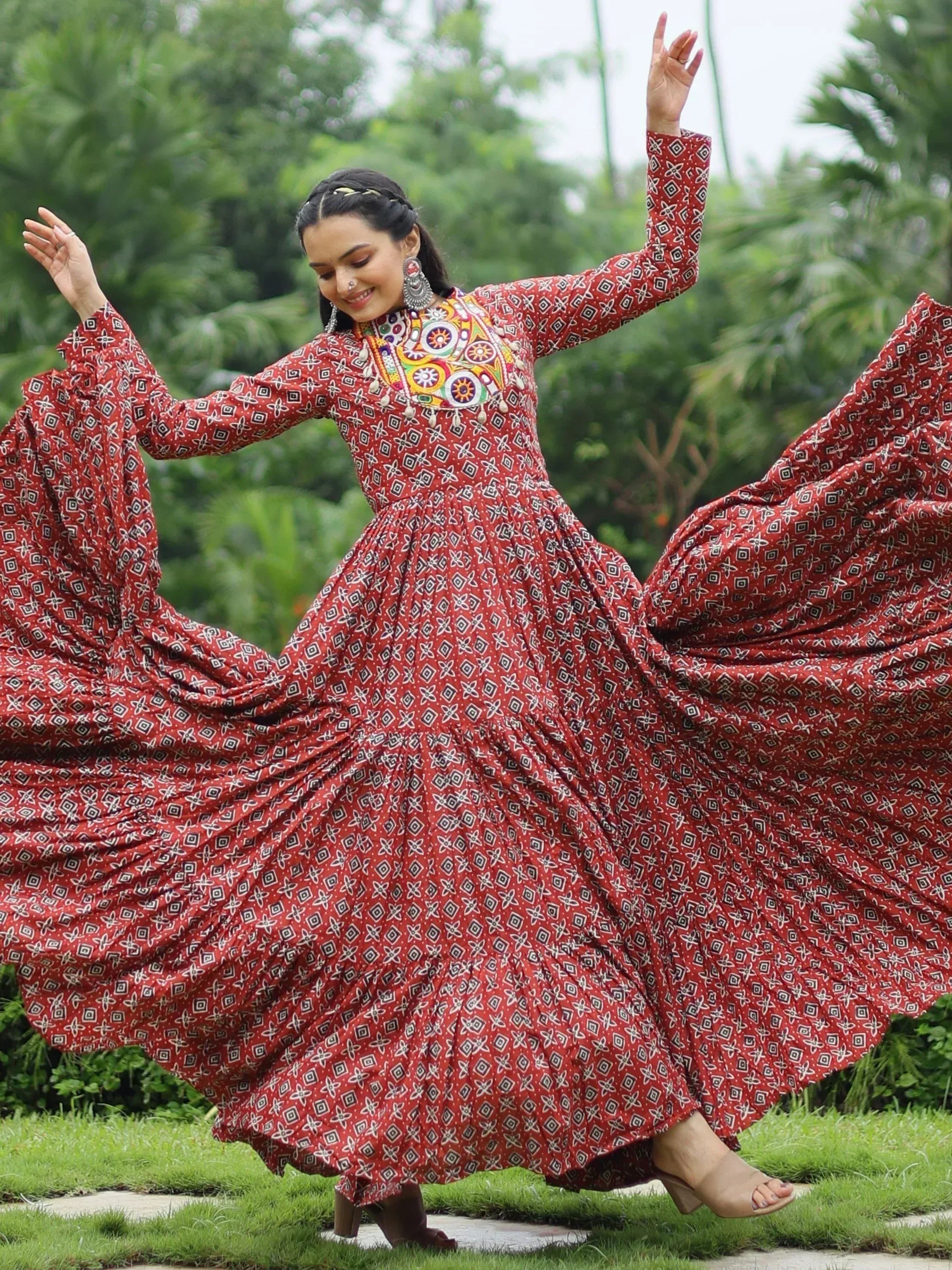 Woman twirling in red printed ethnic gown with mirror work, perfect for Indian festive occasions