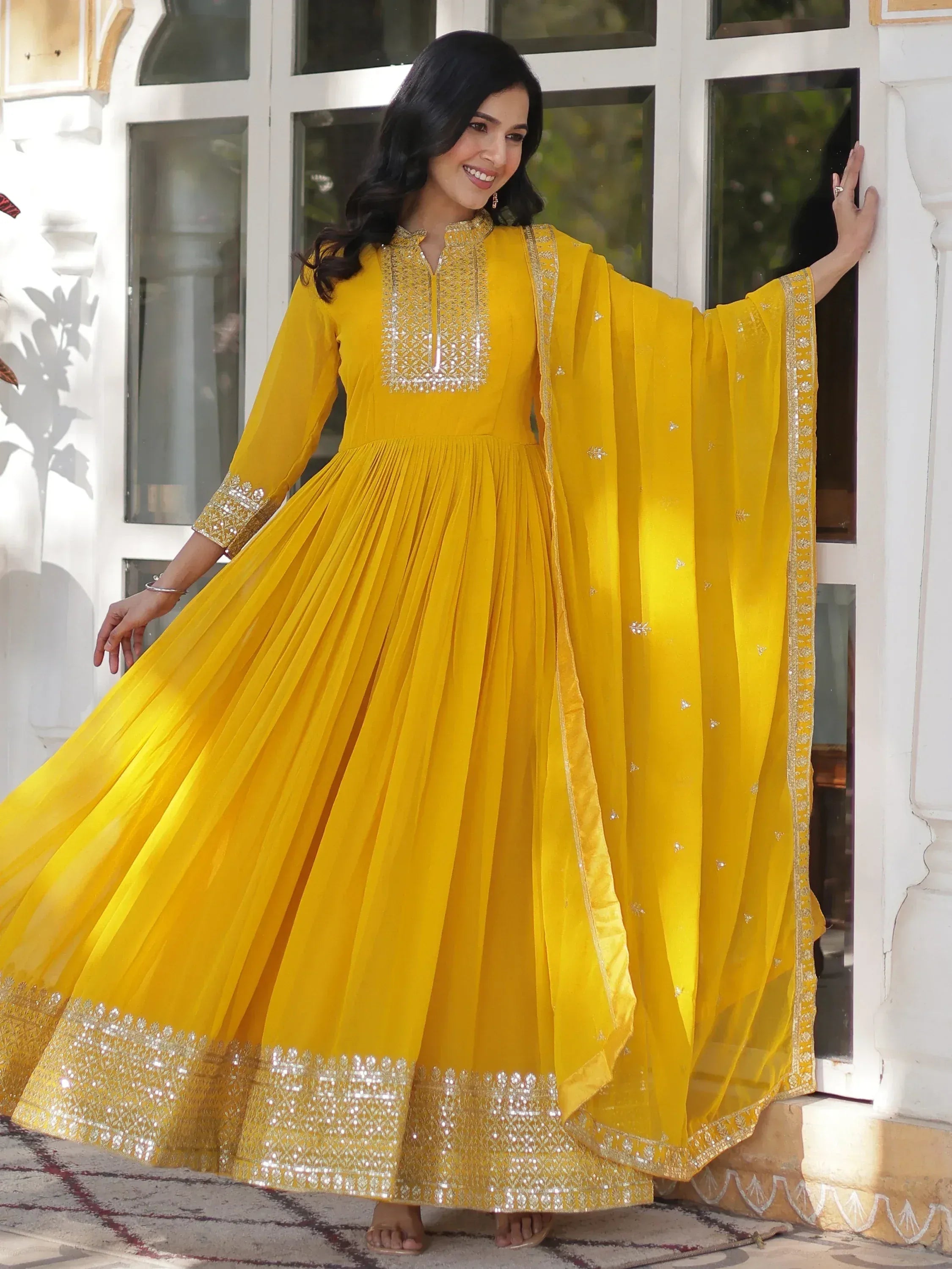 Yellow ethnic gown with intricate embroidery and pleated design, perfect for festive occasions.