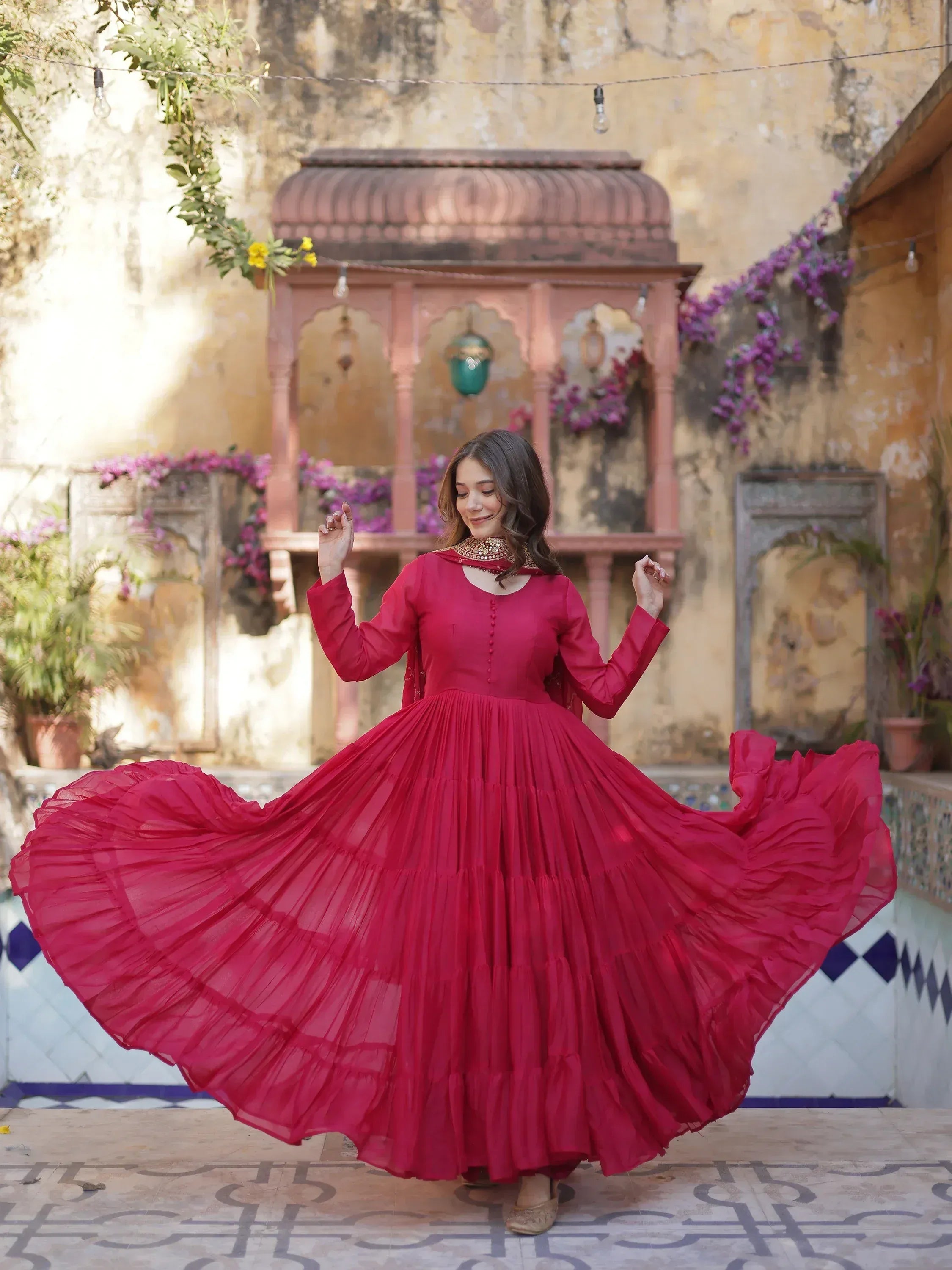 Woman twirling in vibrant red ethnic gown with pleated skirt, perfect for Indian festive occasions