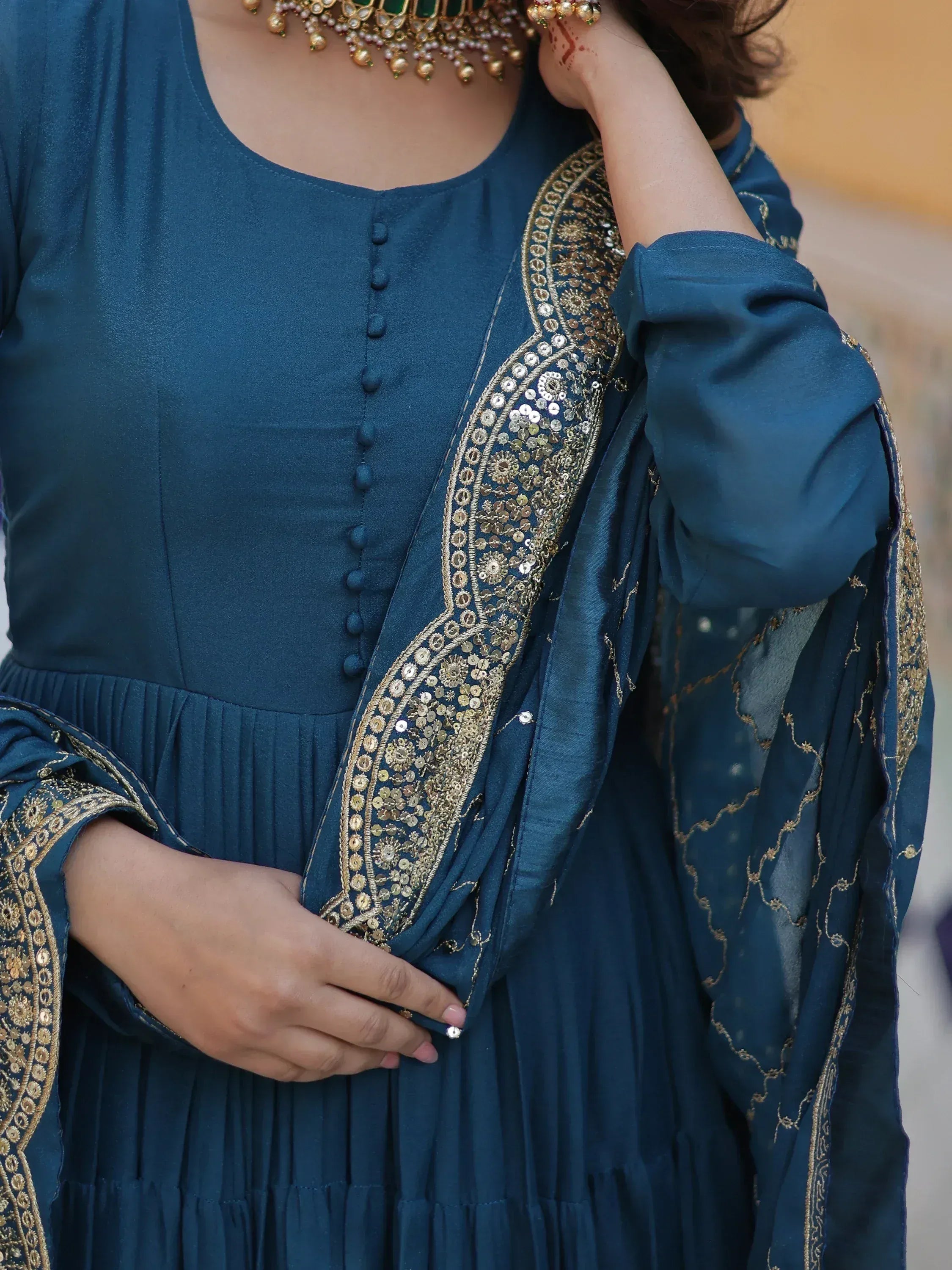 Teal ethnic gown with gold embroidery and sequins, paired with traditional Indian jewelry