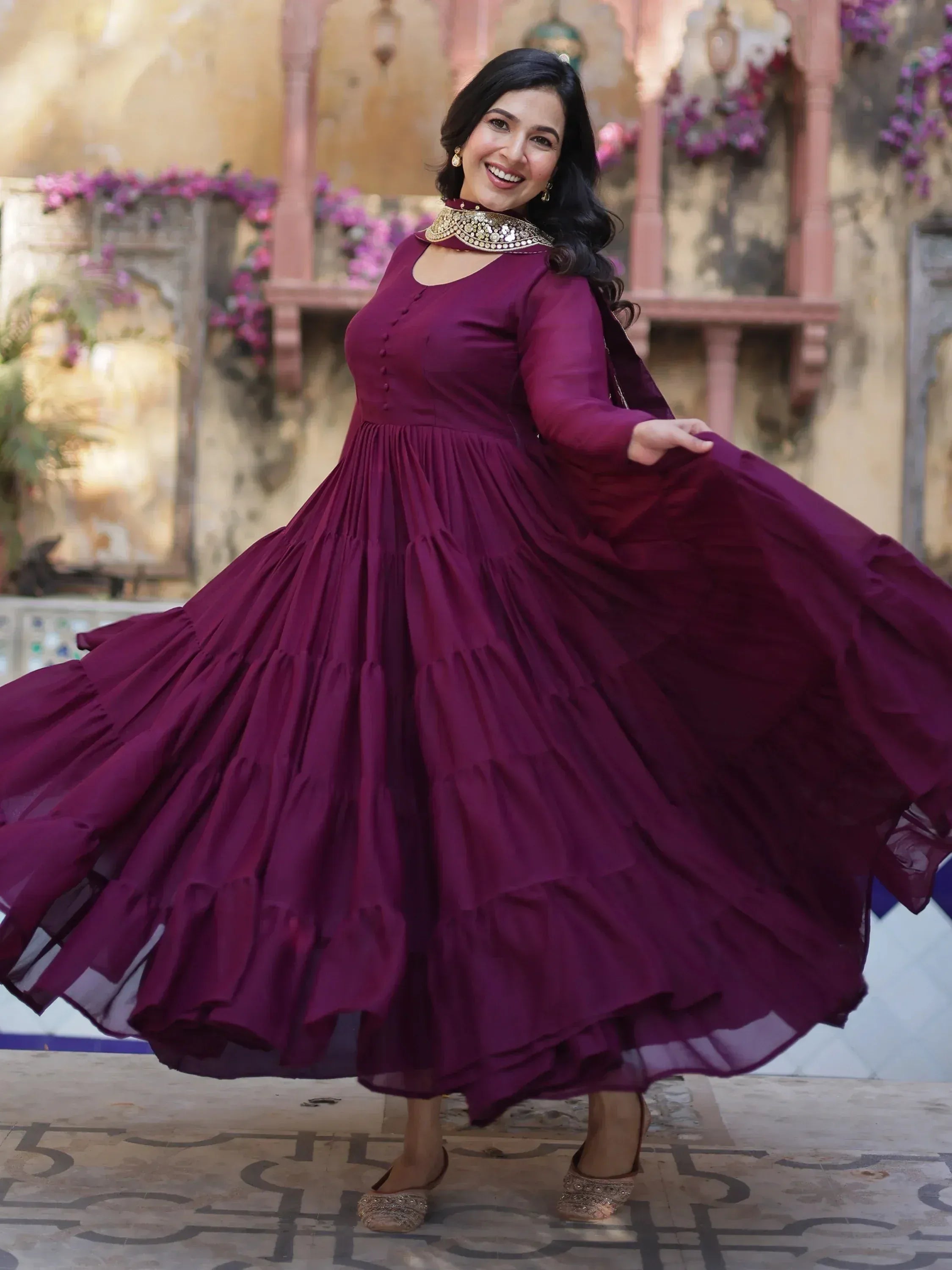 Woman in elegant maroon ethnic gown with flared skirt, perfect for Indian occasions and festive wear.